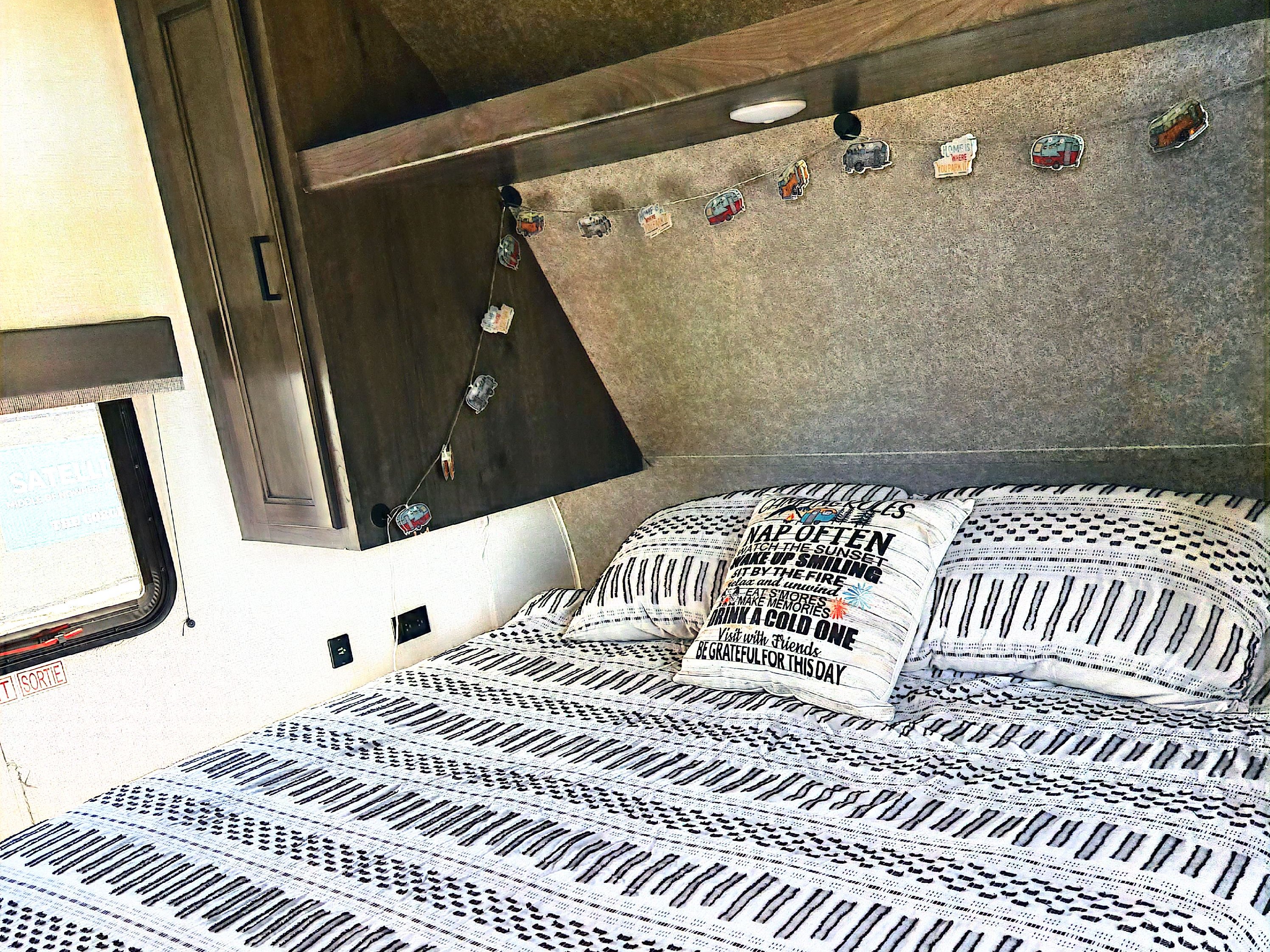 Inviting RV rental bedroom with patterned bedding, text pillow, and charming camper decor. Ready for adventure & relaxation.. Highland Ridge RV Open Range 2021