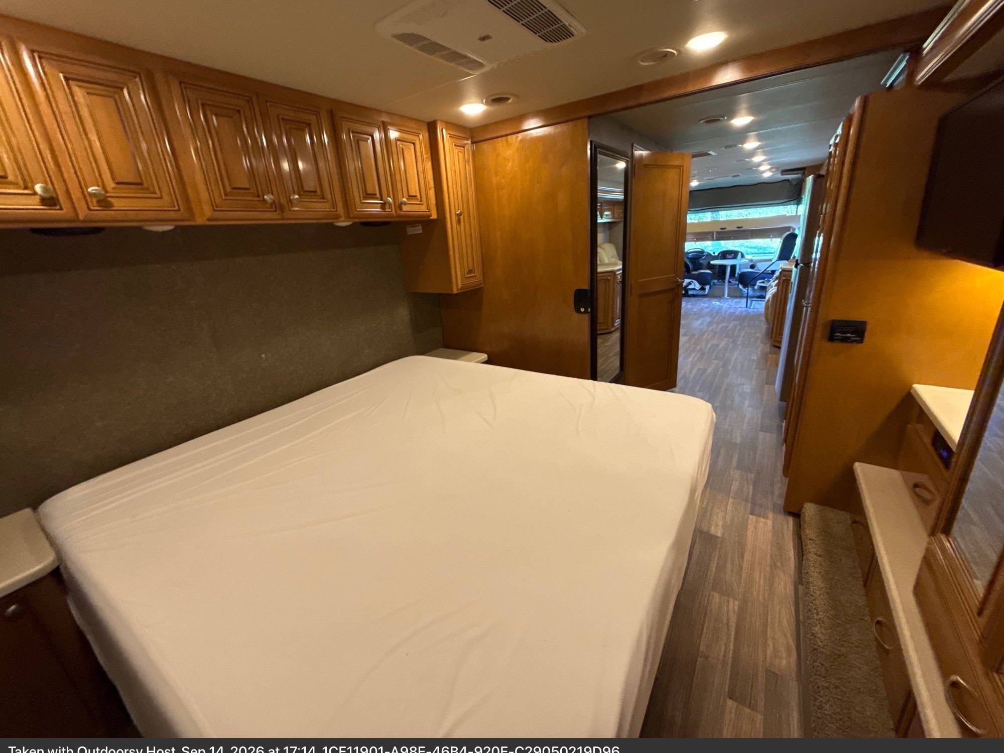 Spacious RV rental bedroom featuring a comfortable bed, wooden cabinets, and an open layout to the living area.. Thor Miramar 2017