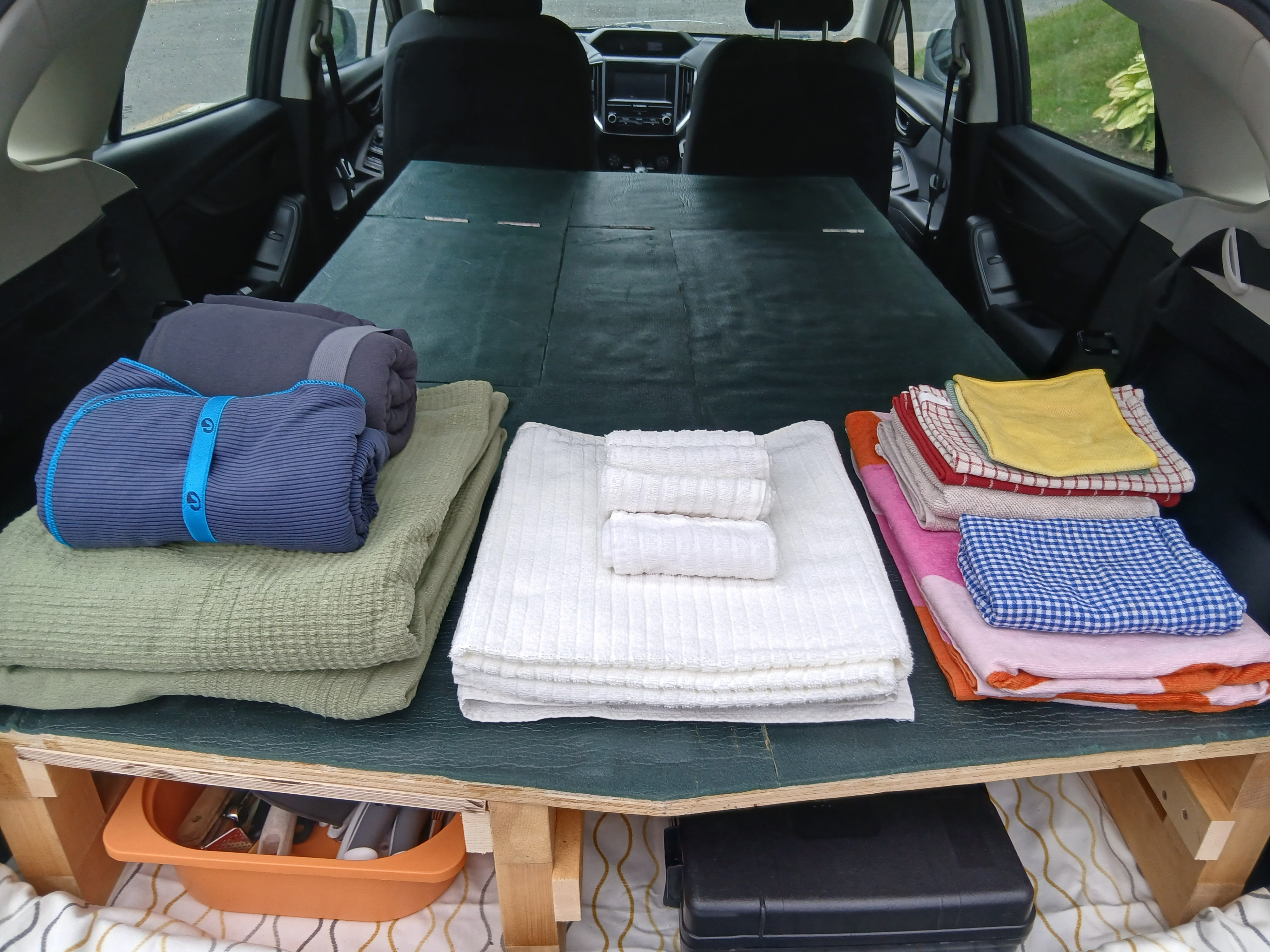 Organized car camping bed setup with neatly stacked linens & under-platform storage, a great RV rental alternative.. Subaru Impreza 2018