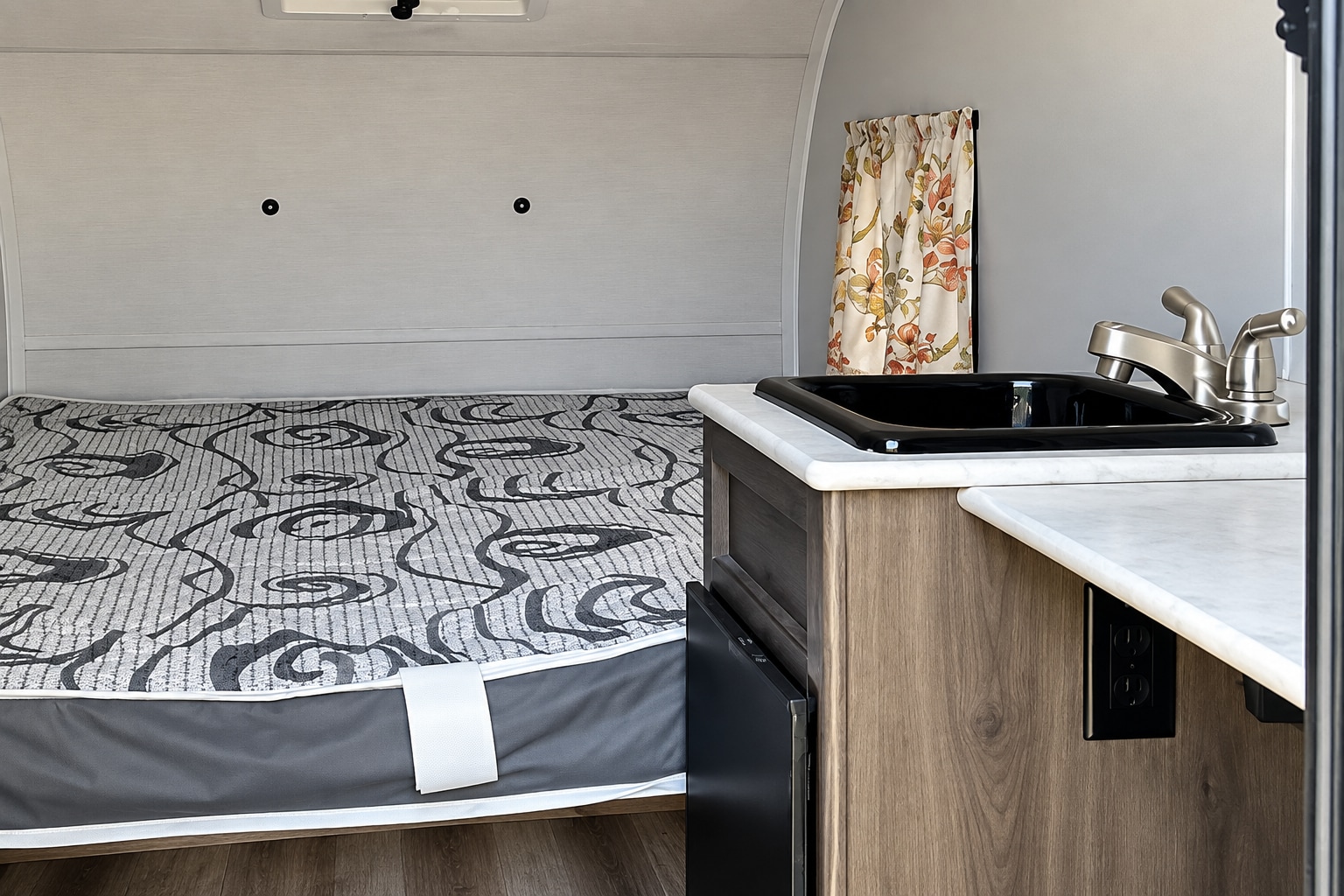 Compact rv rental interior featuring a comfortable bed, a small kitchen sink with faucet, and a mini-fridge.. Coachmen Clipper 2022