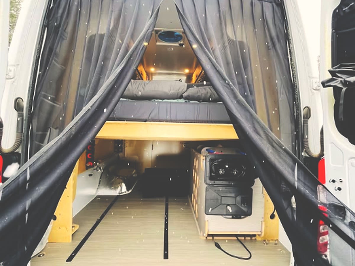 This RV rental camper van features a well-equipped interior: a raised bed, portable fridge, and convenient storage.. Van Cruiser United Haven Custom Built 2015