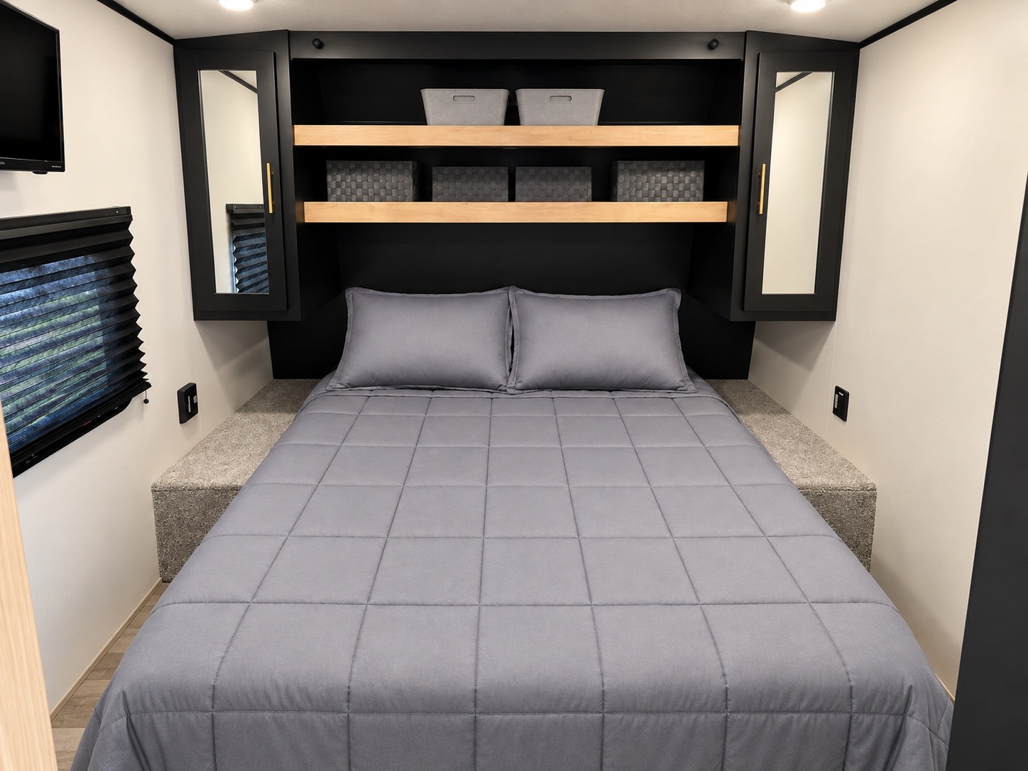 Comfortable RV rental bedroom with a neatly made gray bed, built-in storage shelves, and mirrored side cabinets.. Keystone RV Springdale 2022