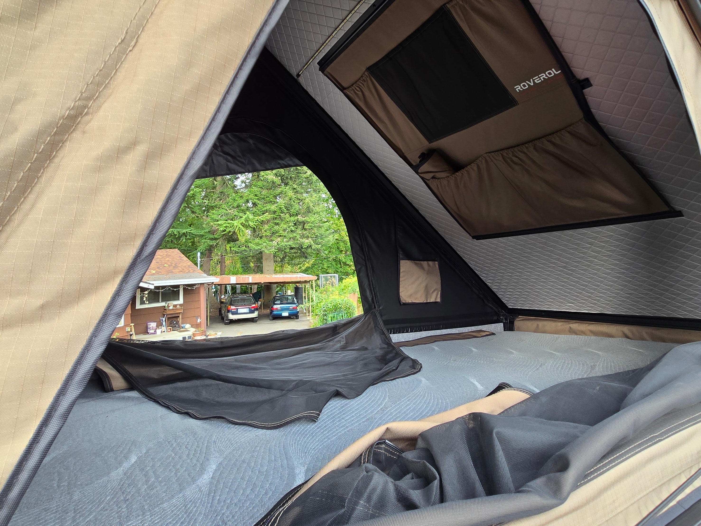 Inside a Roverol rooftop tent, perfect for an RV rental trip, offering a comfortable view of a suburban backyard.. Ford Transit 2017