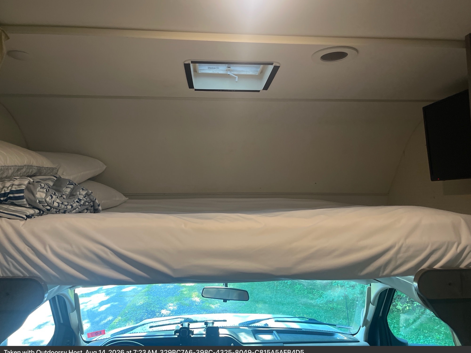 This RV rental offers a comfy overhead bed with white linens, a ceiling skylight, and a front cab view.. Winnebago Minnie Winnie 2018