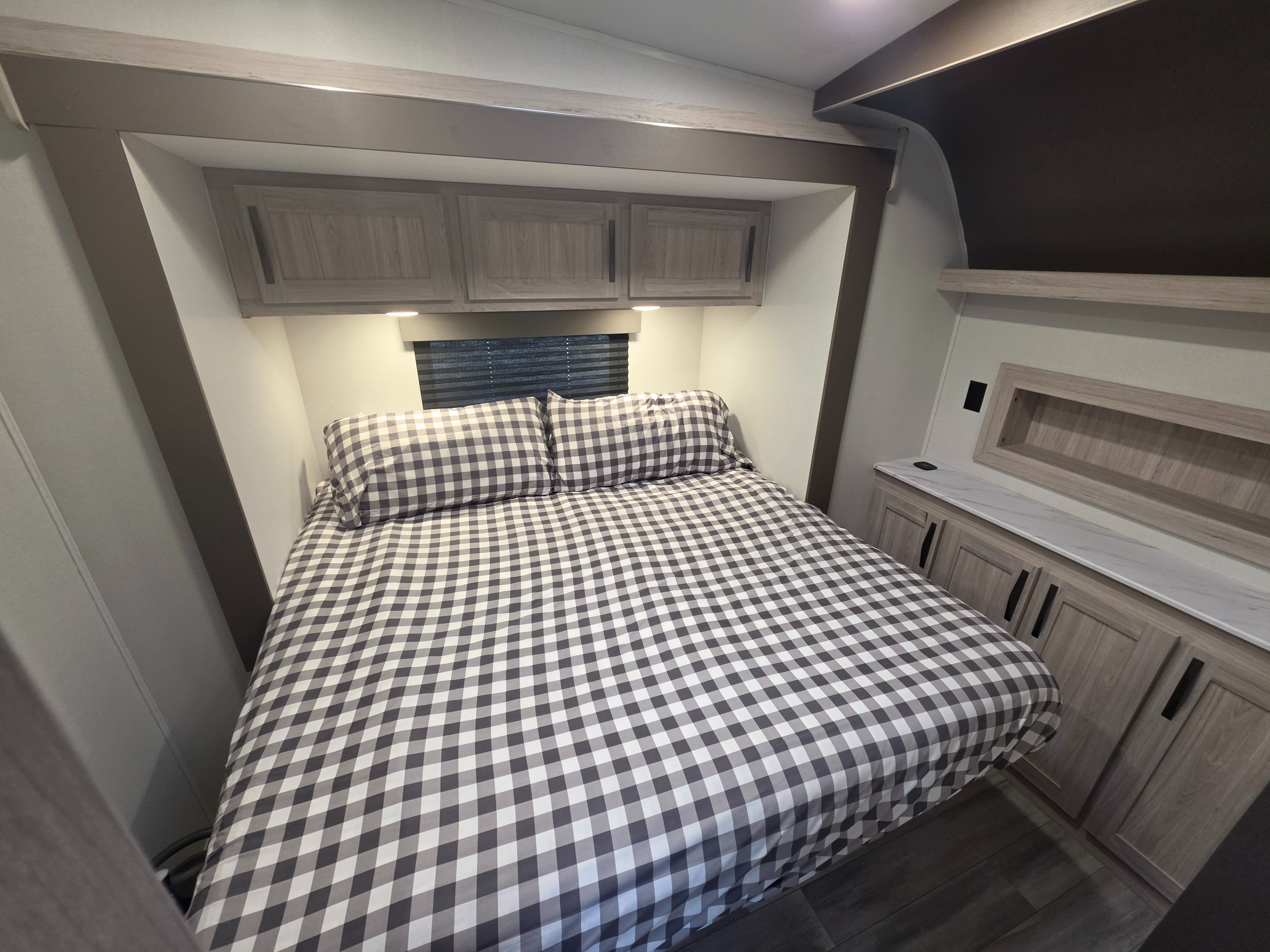 Cozy RV rental bedroom with gray gingham bedding, overhead cabinets, and side storage. Ideal for a comfortable getaway.. Cruiser Rv Corp Stryker 2025