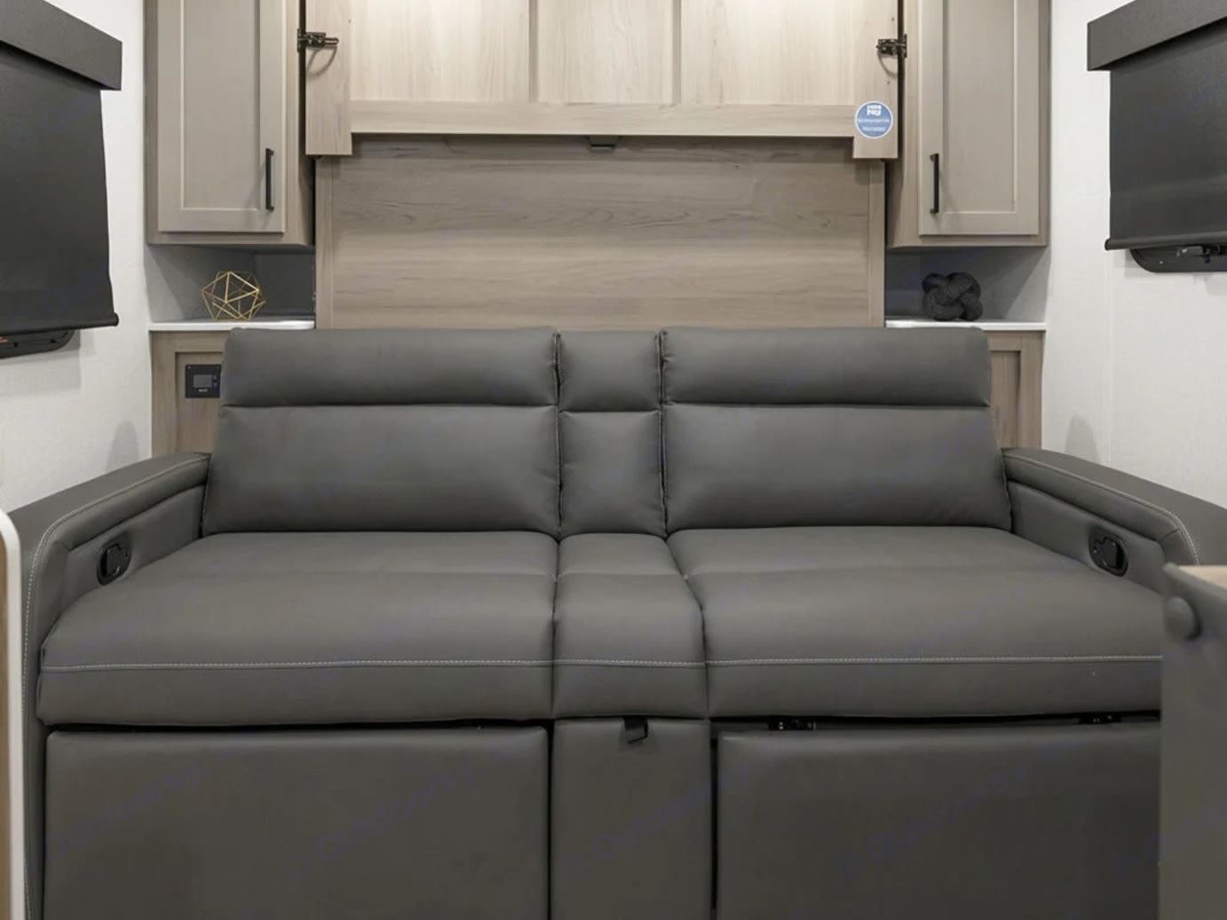 RV rental interior featuring a modern grey reclining sofa with cabinets & wall paneling in a compact living space.. Forest River Flagstaff E-Pro 2019
