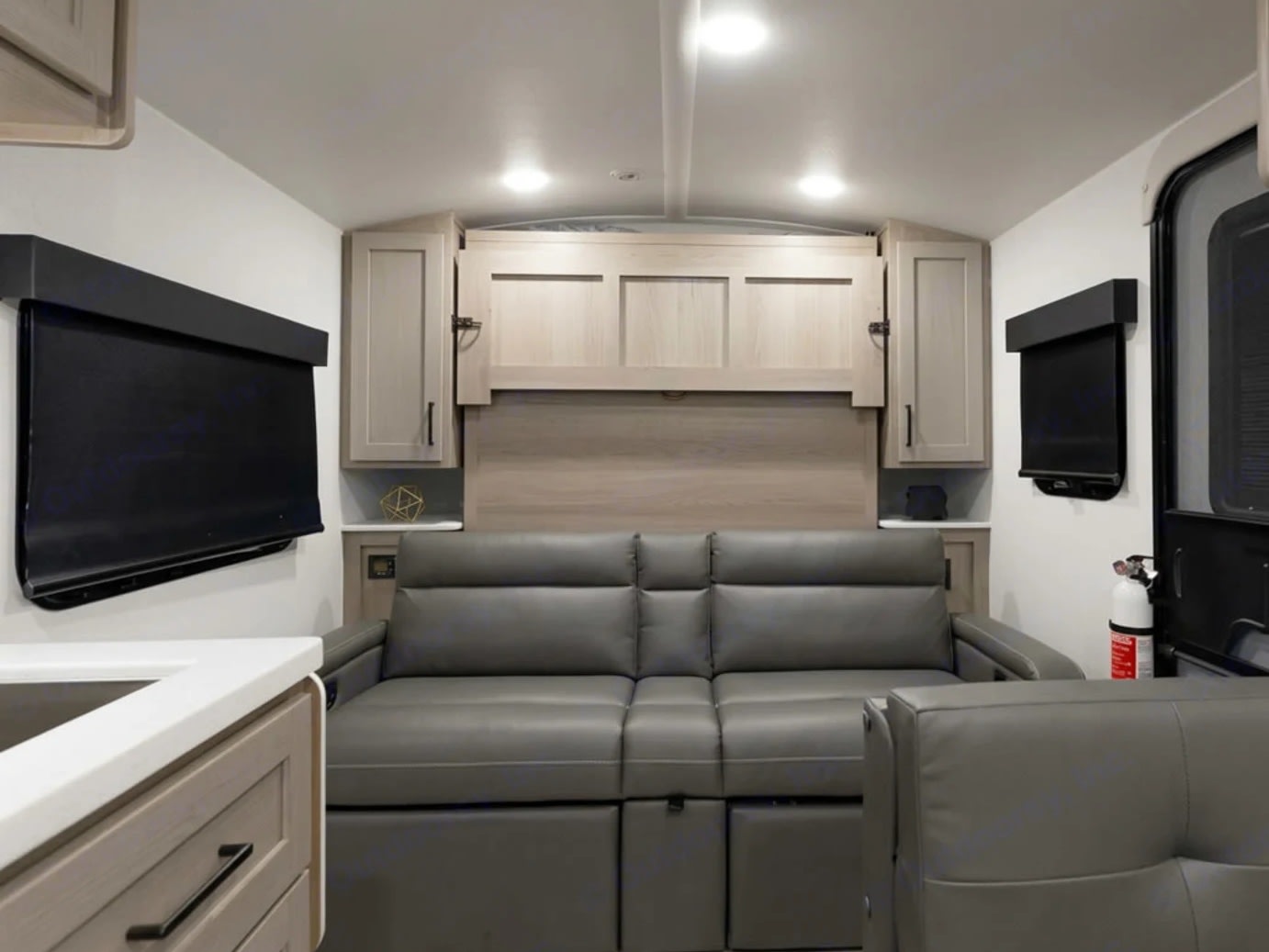 RV rental interior: a gray sofa below a concealed Murphy bed, flanked by modern cabinetry, optimizing compact living.. Forest River Flagstaff E-Pro 2019