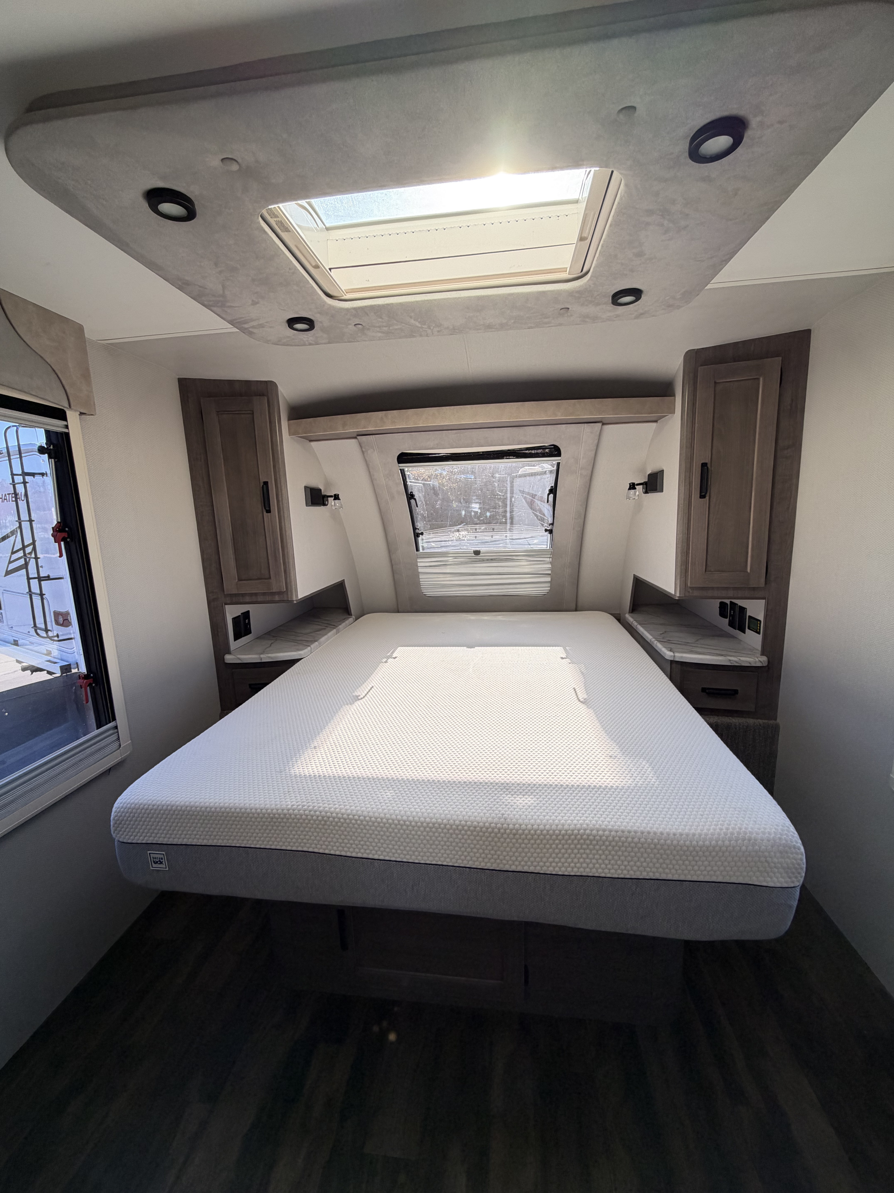 Modern RV rental bedroom with a large bed, overhead skylight, and bedside storage. Ideal for comfortable travel.. lance 2075 2021
