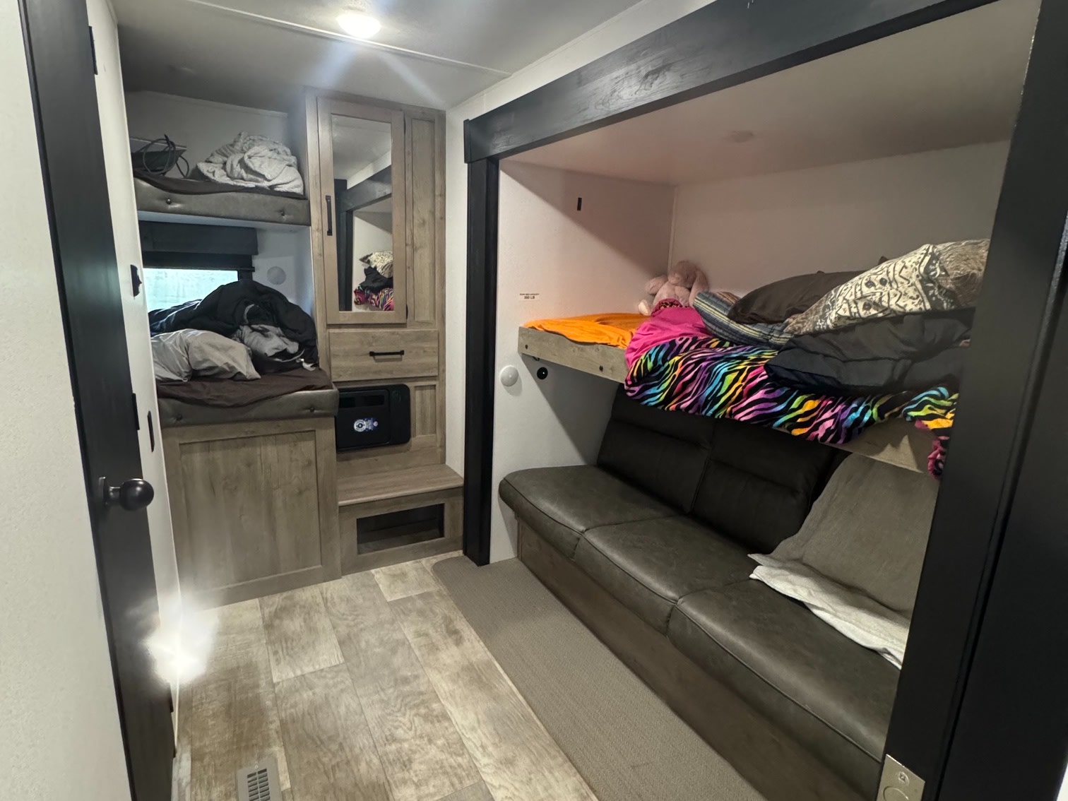 RV rental interior: cozy bunk beds (two on left, one above sofa) and a comfortable sofa provide ample sleeping and seating space.. Forest River Palomino Puma 2025