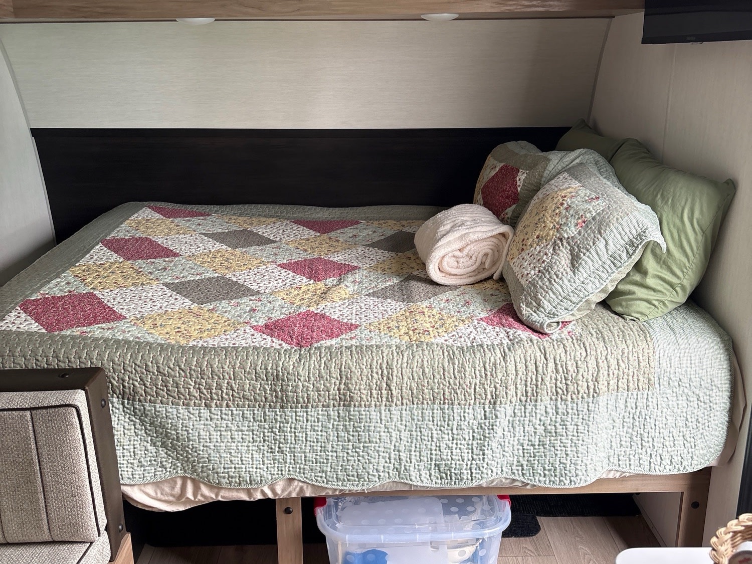 Cozy RV rental bedroom with a colorful patchwork quilt, pillows, and under-bed storage, ready for your trip.. Forest River Cherokee Wolf Pup 2025