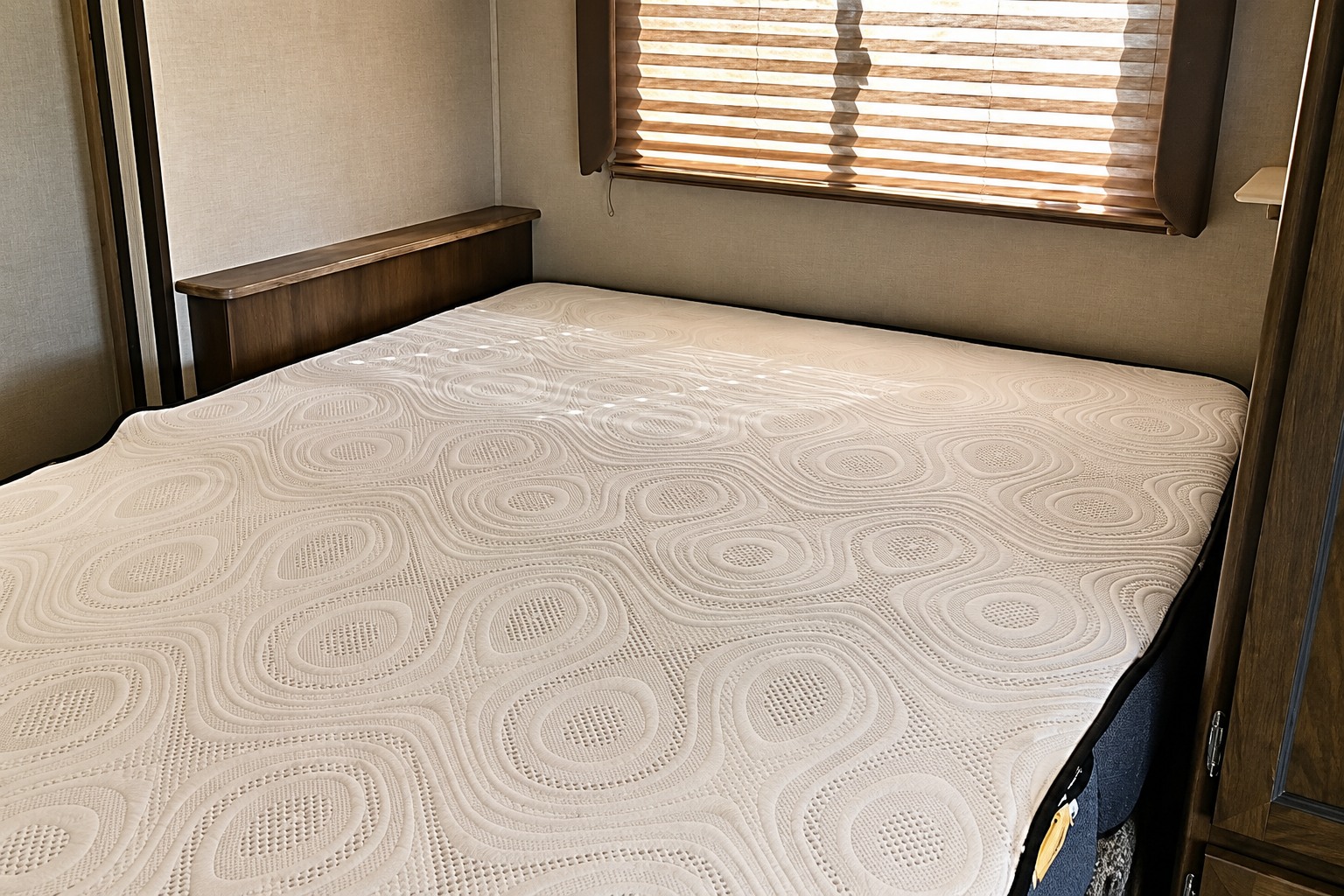 RV rental bedroom featuring a neatly textured mattress, wooden headboard, and blinds, perfect for a cozy night's rest.. Forest River Coachmen Freelander 2018