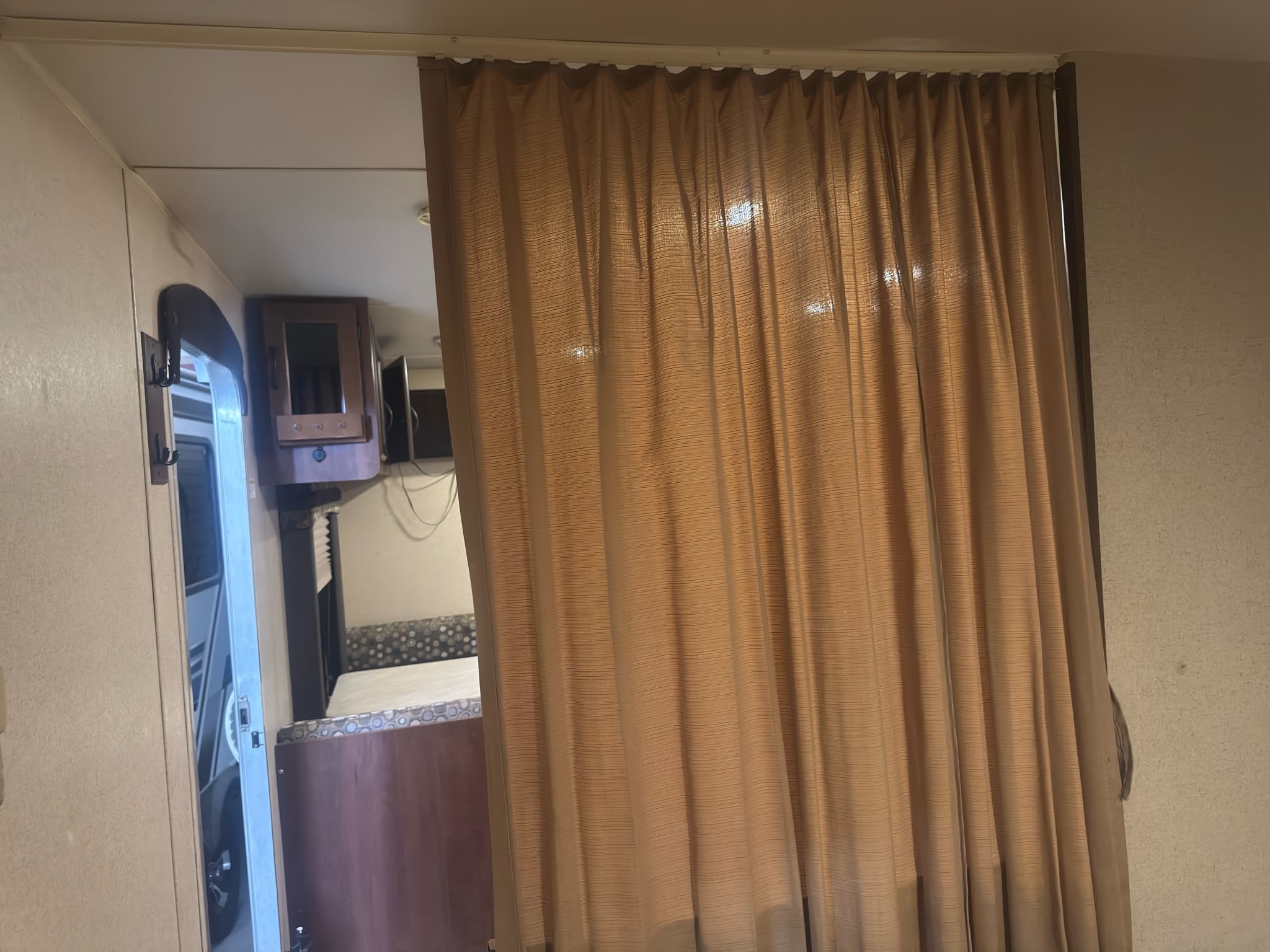 RV rental interior: A drawn brown curtain forms a privacy partition, with cabinets, a dinette, and a doorway visible.. Jayco Jay Flight 2015