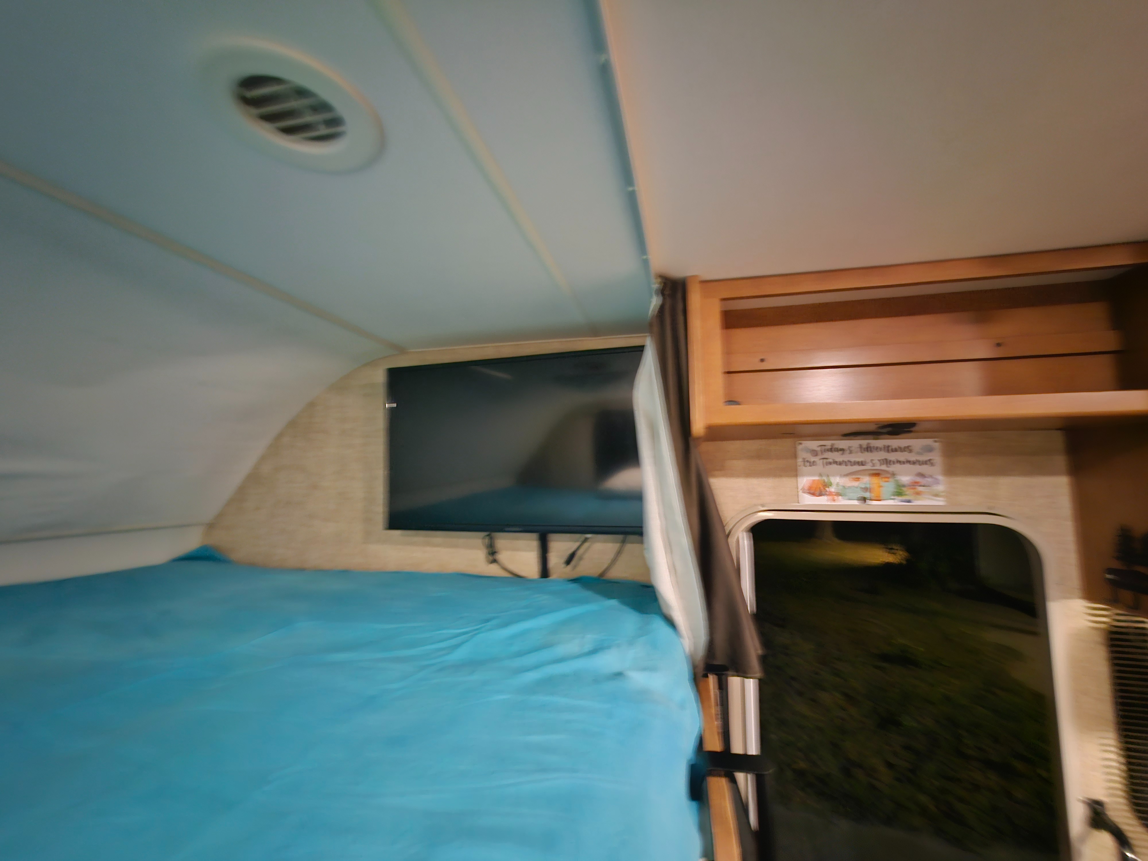 RV rental interior: a cozy bed, wall-mounted TV, overhead cabinets, and ceiling vent visible for a comfortable trip.. Winnebago Minnie Winnie 2018