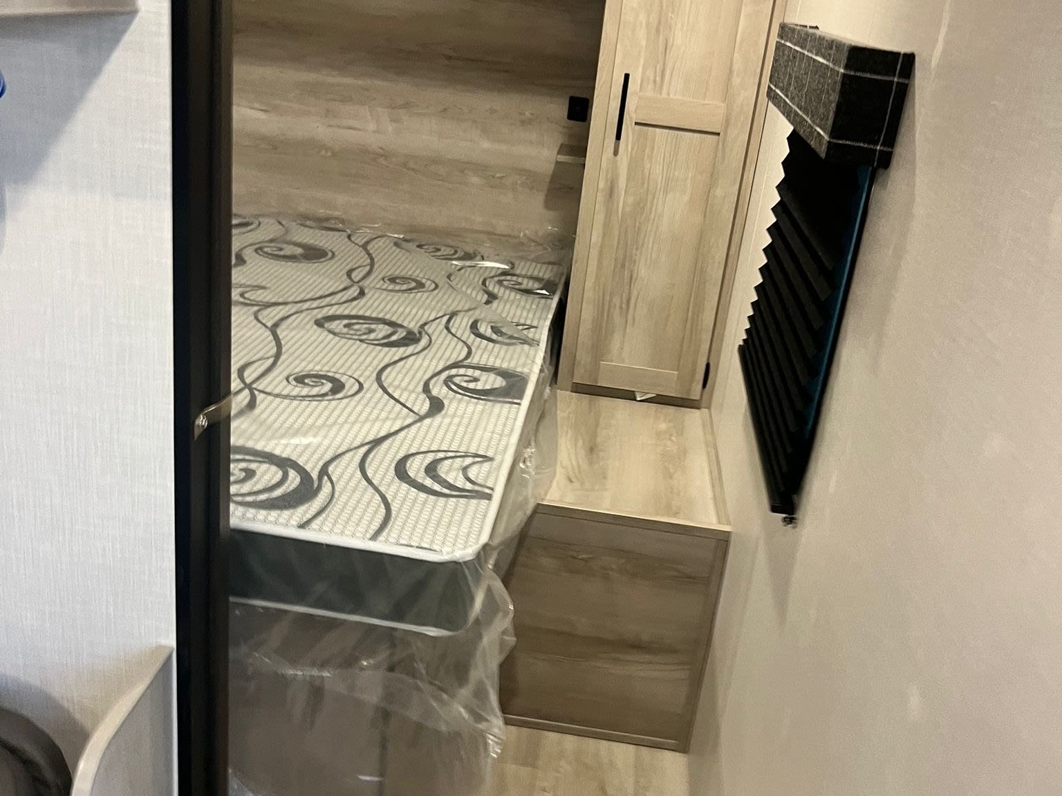 Inside an RV rental: a neat bedroom with a new mattress, overhead shelf, and built-in wardrobe for storage.. Other Other 2024