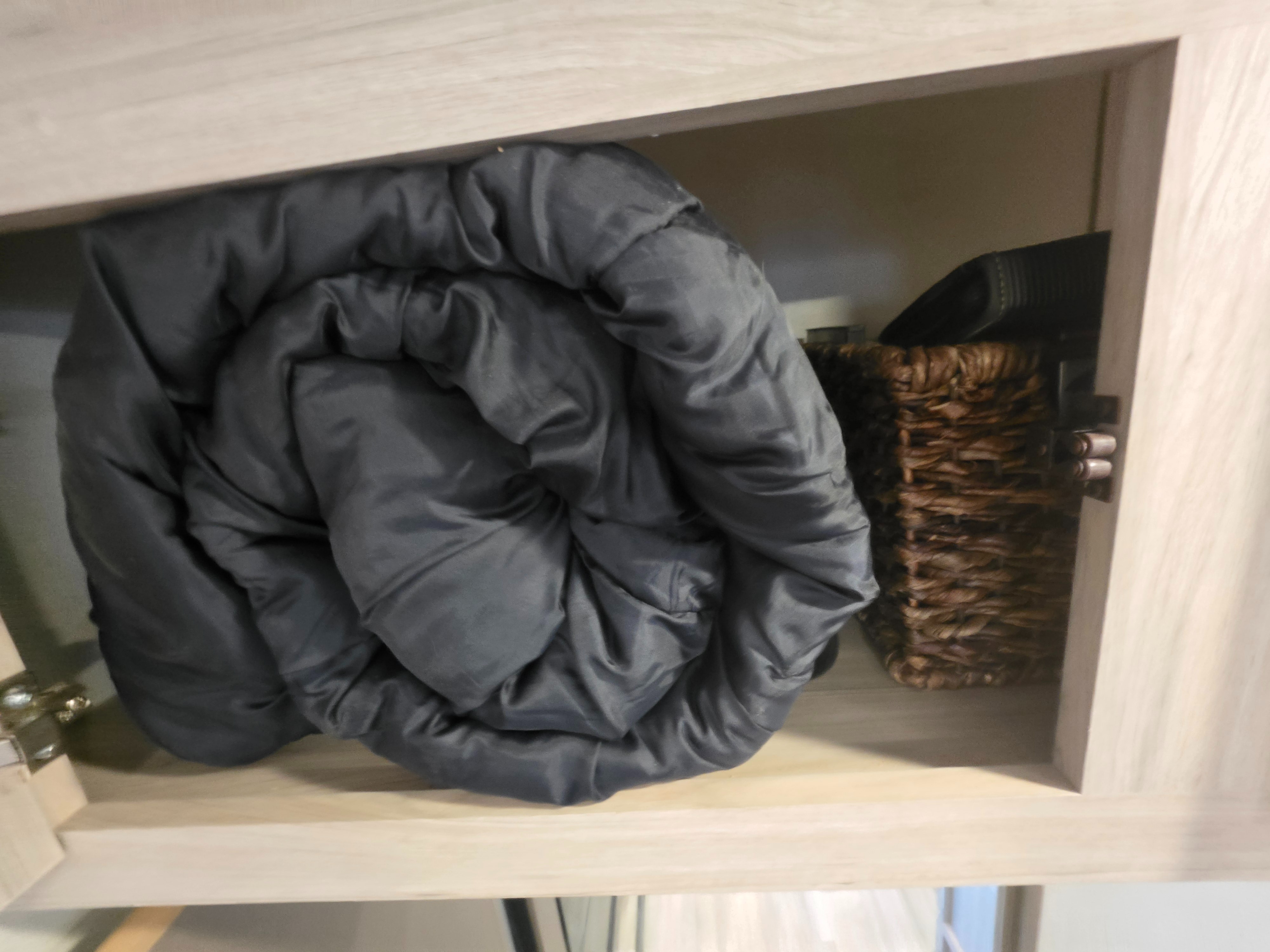 RV rental storage: A dark grey, rolled blanket and a woven basket neatly tucked into a light wood cabinet.. Cruiser Rv Corp Stryker 2025