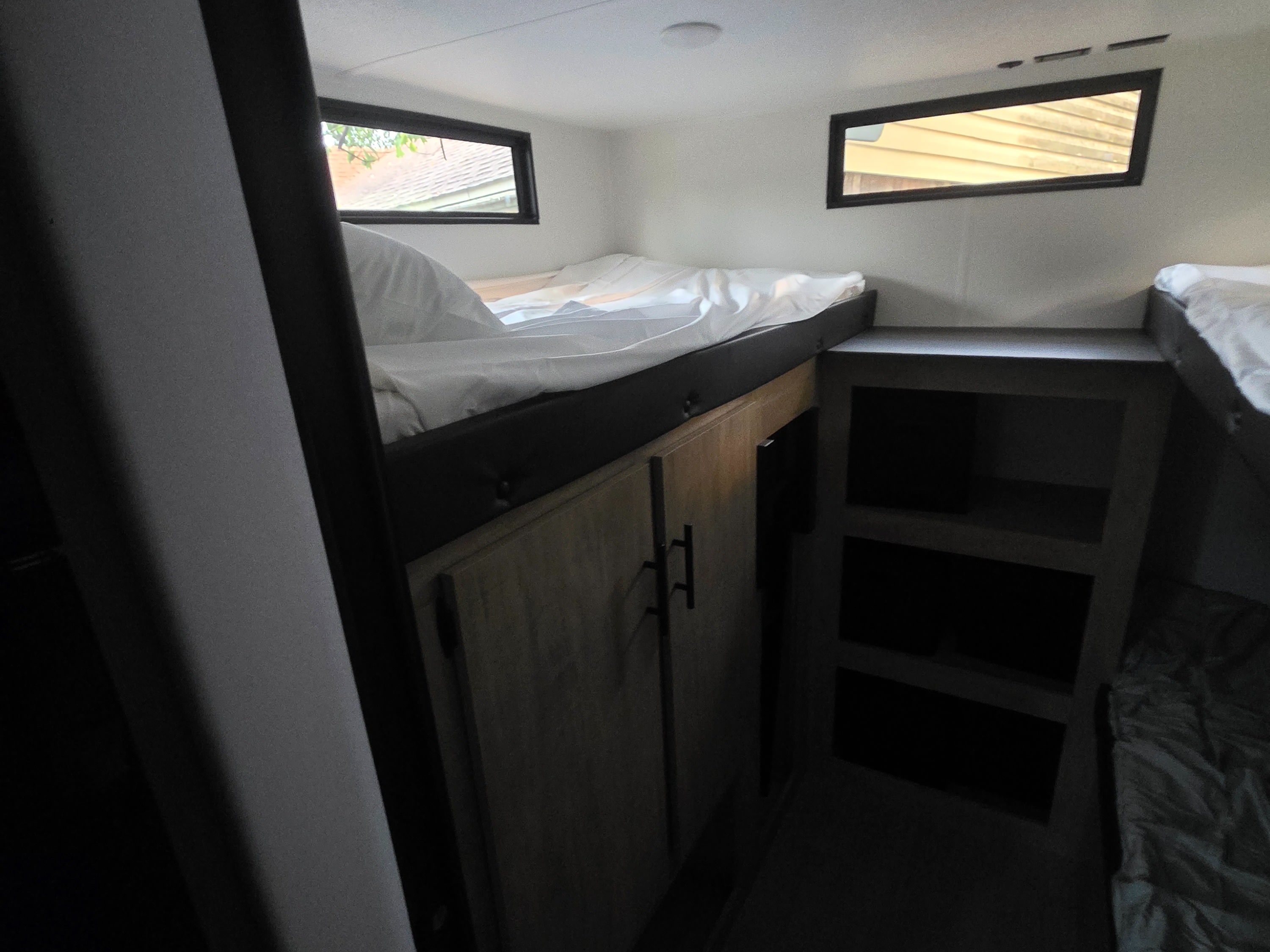 Cozy RV rental bunk beds with built-in storage and natural light from windows create a functional sleeping area.. Forest River 29TJ 2027