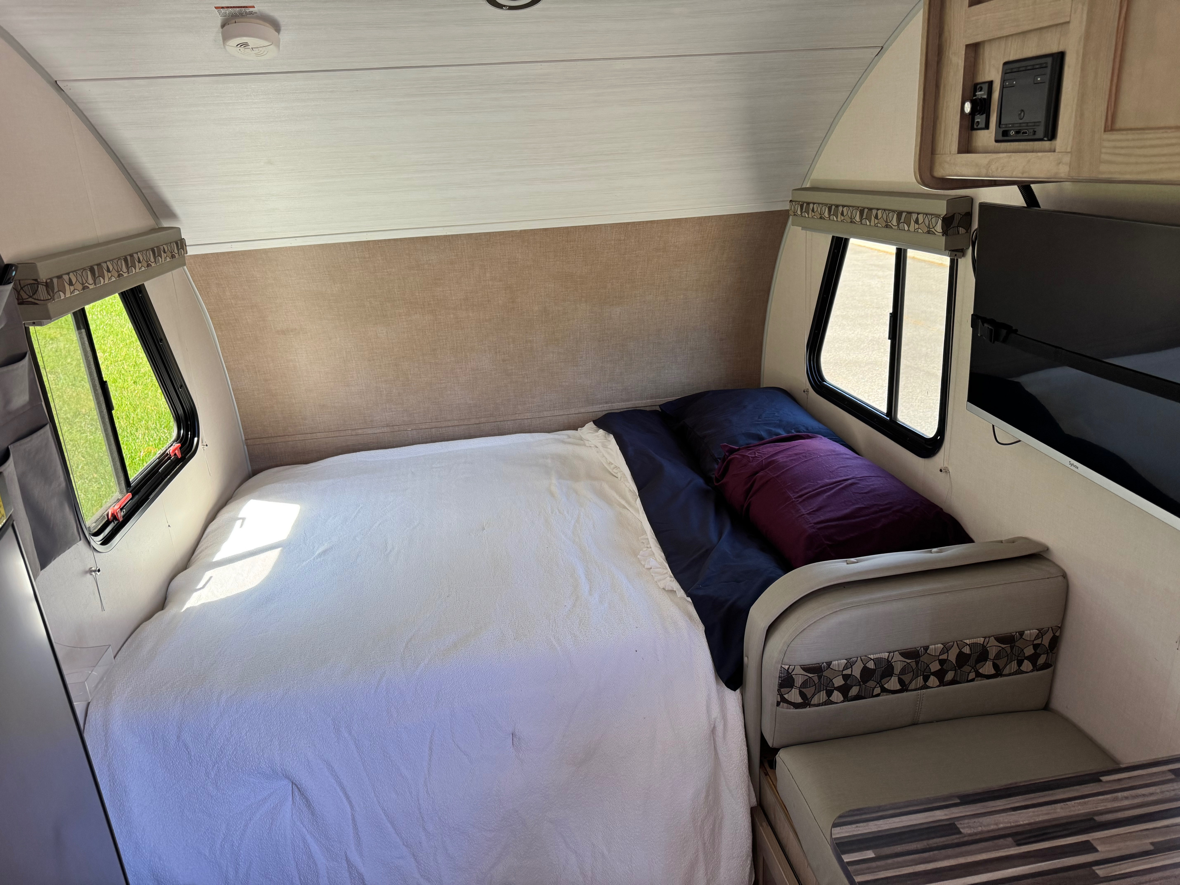 Cozy RV rental interior with a comfortable bed, windows, small dinette, and TV, ideal for travel adventures.. R-Pod R-Pod Trailer 2020
