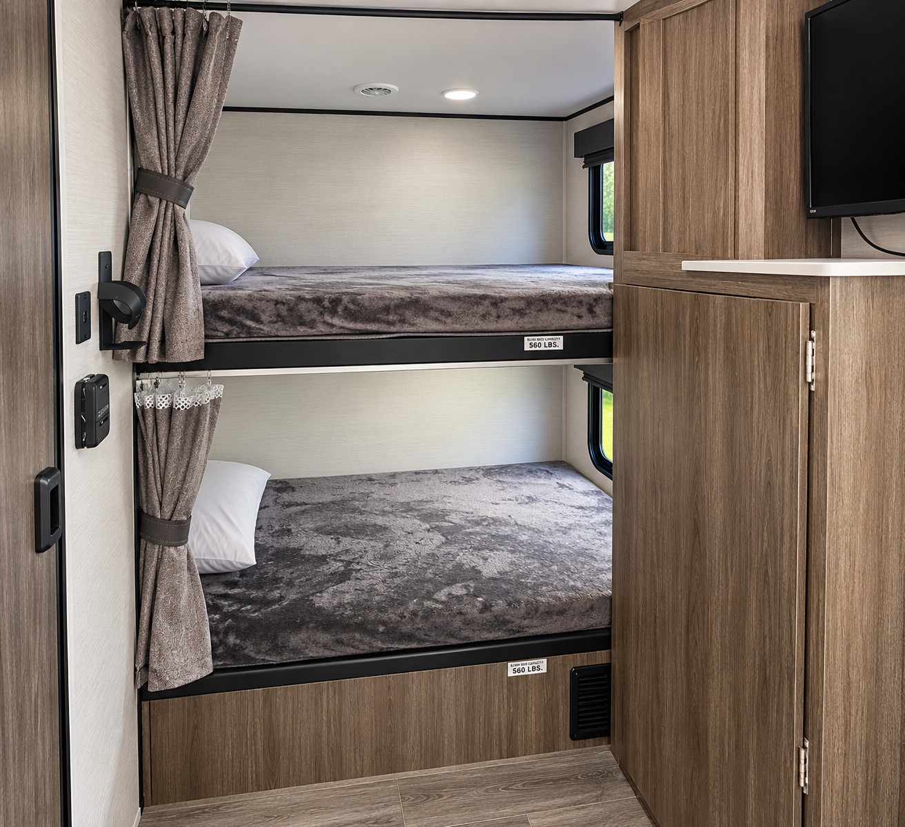 Cozy RV rental bunk beds with privacy curtains and soft bedding. A built-in cabinet and TV are to the right.. Venture Sonic 2025
