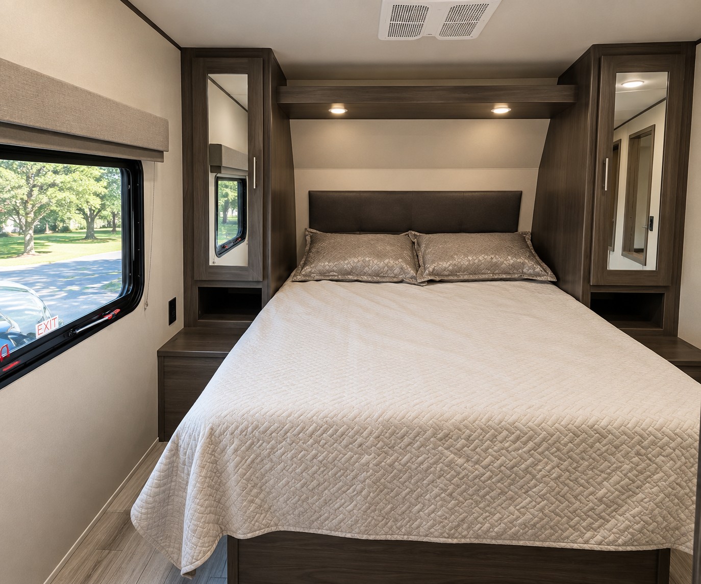 Comfortable RV rental bedroom with a queen bed, overhead lighting, bedside cabinets, and a window with scenic views.. Grand Design Transcend Xplor 2022