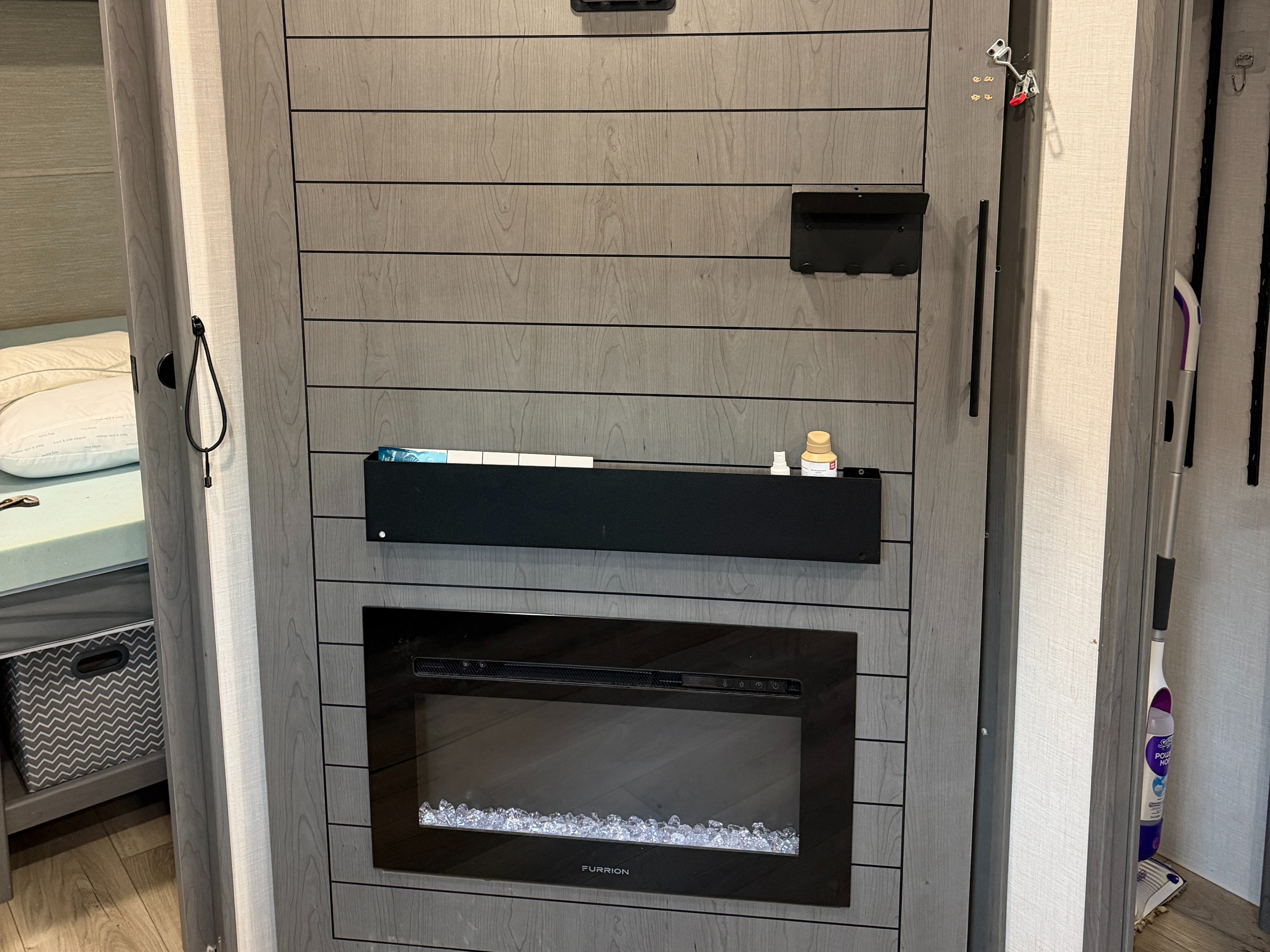 Compact RV rental interior featuring a modern electric fireplace, wall storage, and a peek into the sleeping area.. Forest River 2690BHK Ozark 2025