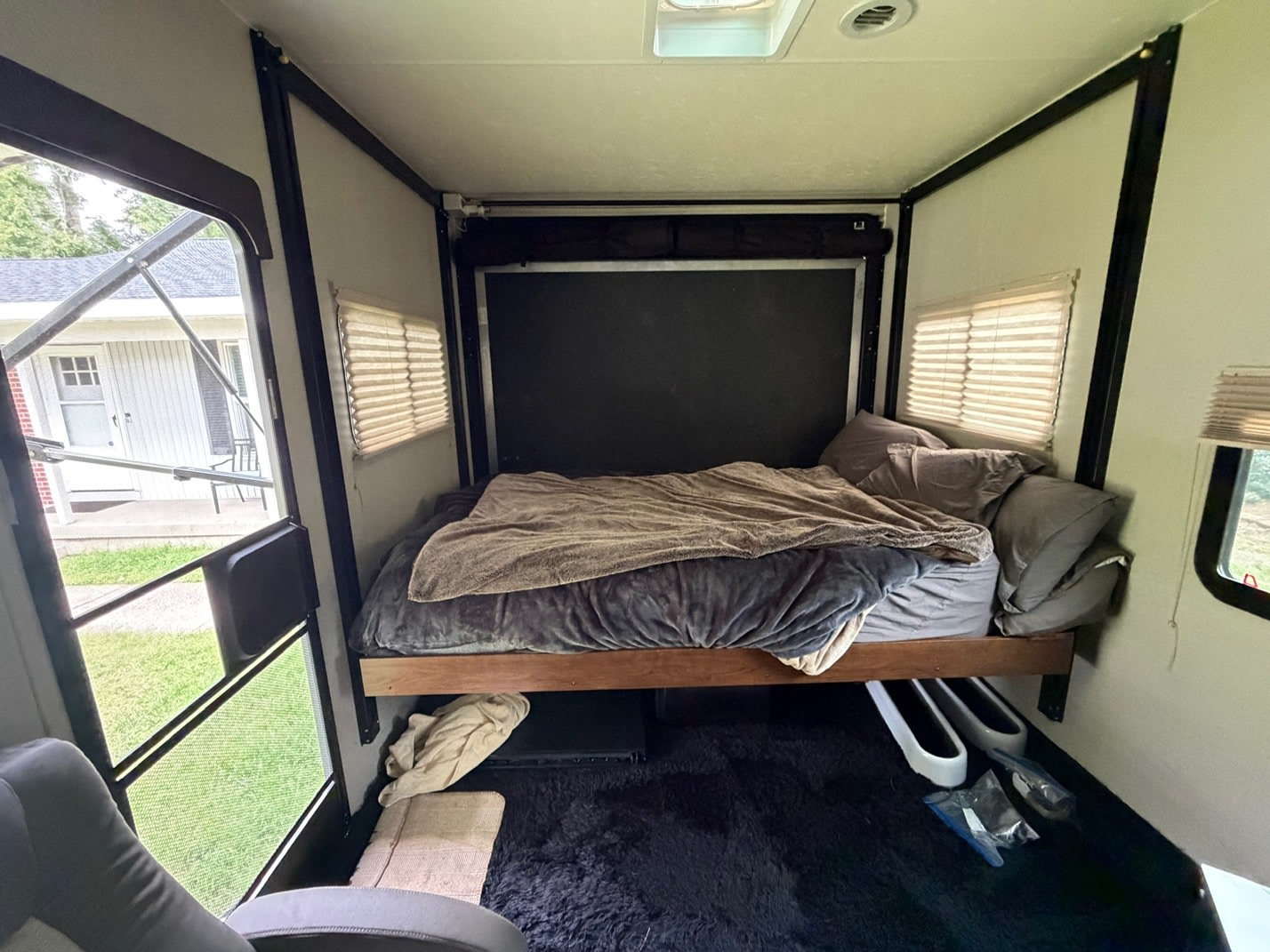 RV rental interior: cozy bedroom with a comfortable bed, pillows, blankets, dark plush rug, and windows. Ready for your trip!. Coachmen Freedom Express 2017