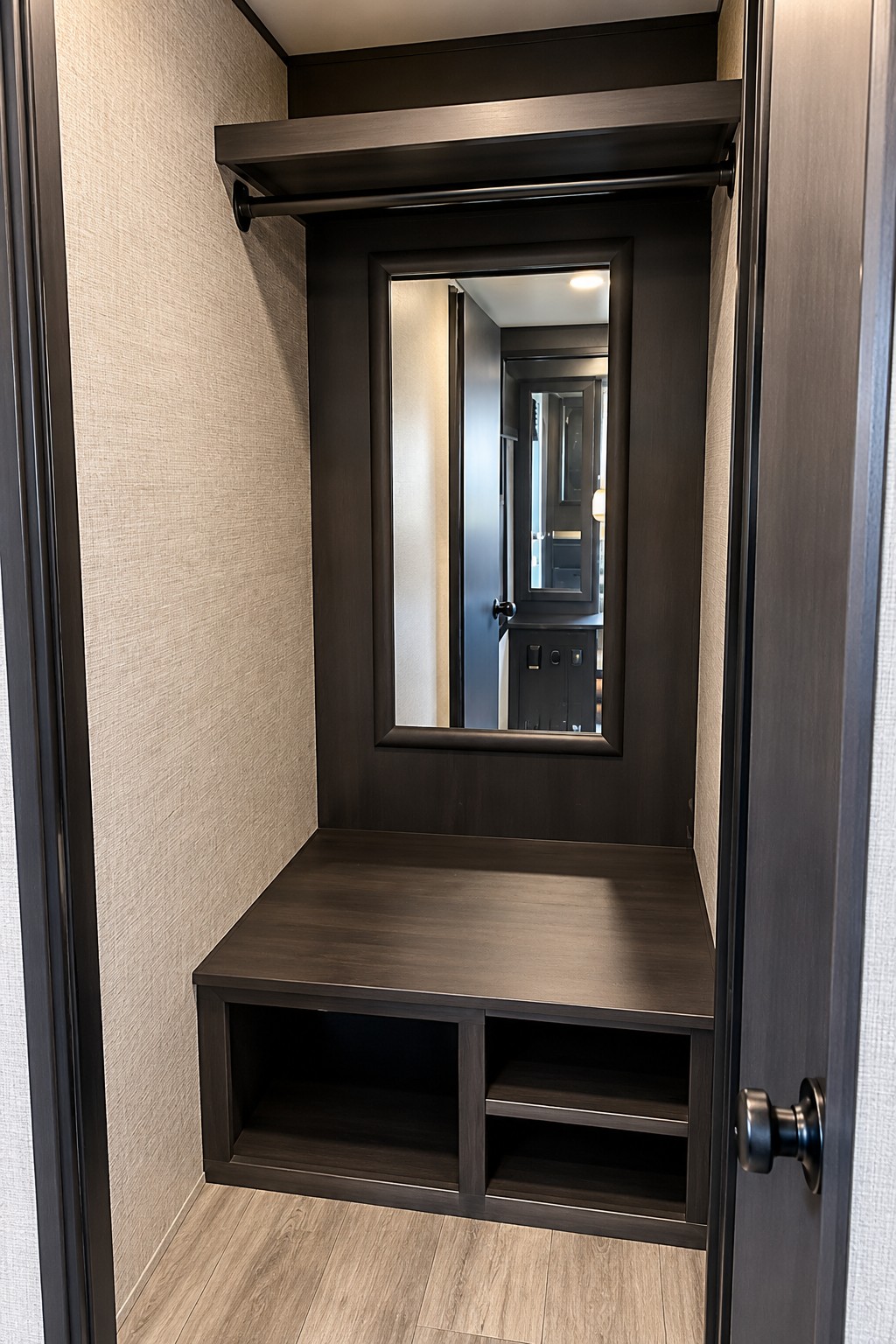 RV rental interior: a dark wood closet/entryway with an integrated mirror, top shelf, hanging rod, bench seating, and lower storage shelves.. Jayco White Hawk 2022