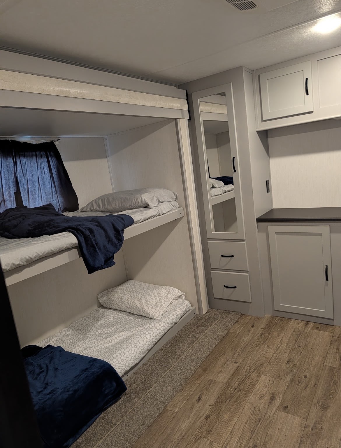 Cozy RV rental sleeping area with bunk beds, ready bedding, mirror, & built-in storage for a comfortable stay.. Forest River Vibe 2021