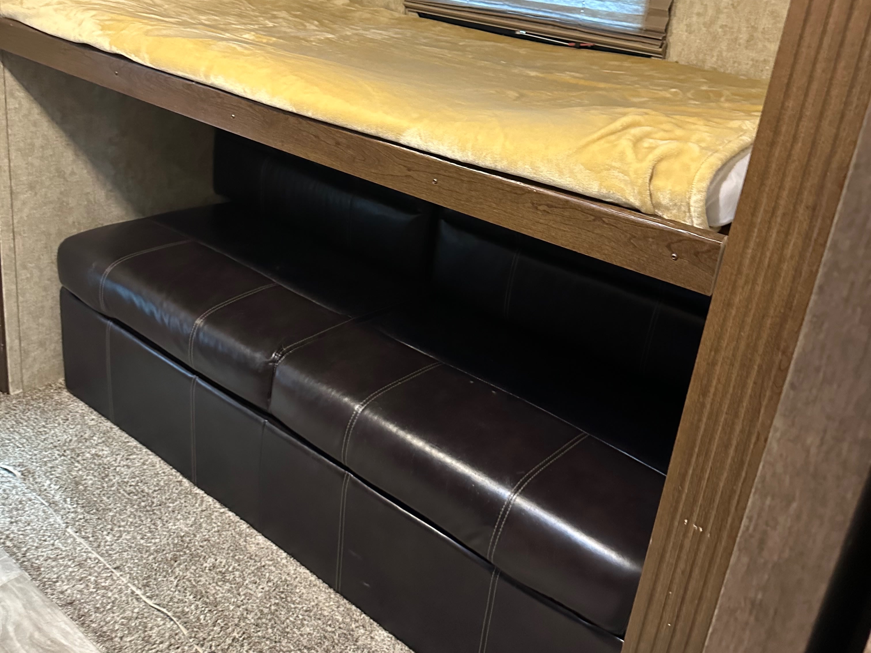 Inside an RV rental, a cozy top bunk with a yellow blanket is above a brown leather sofa, ideal for compact living.. Crusader Crusader Fifth Wheel 2018