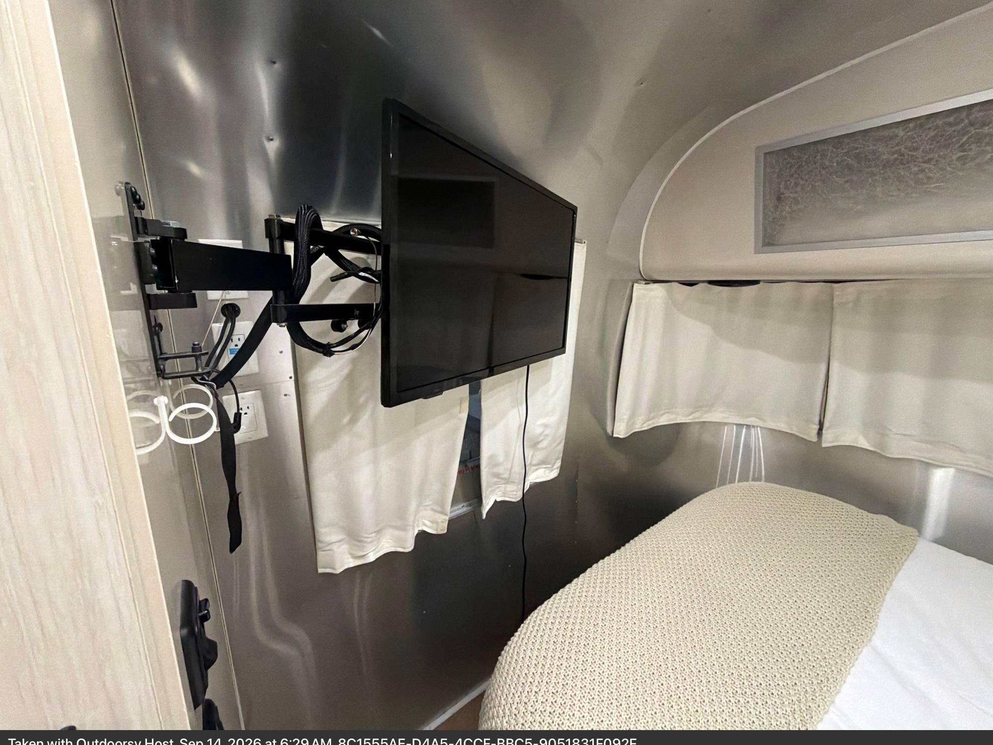 Cozy rv rental bedroom interior: TV mounted on metallic wall, bed with blanket, and curtains. Your mobile retreat awaits.. Airstream International 2017