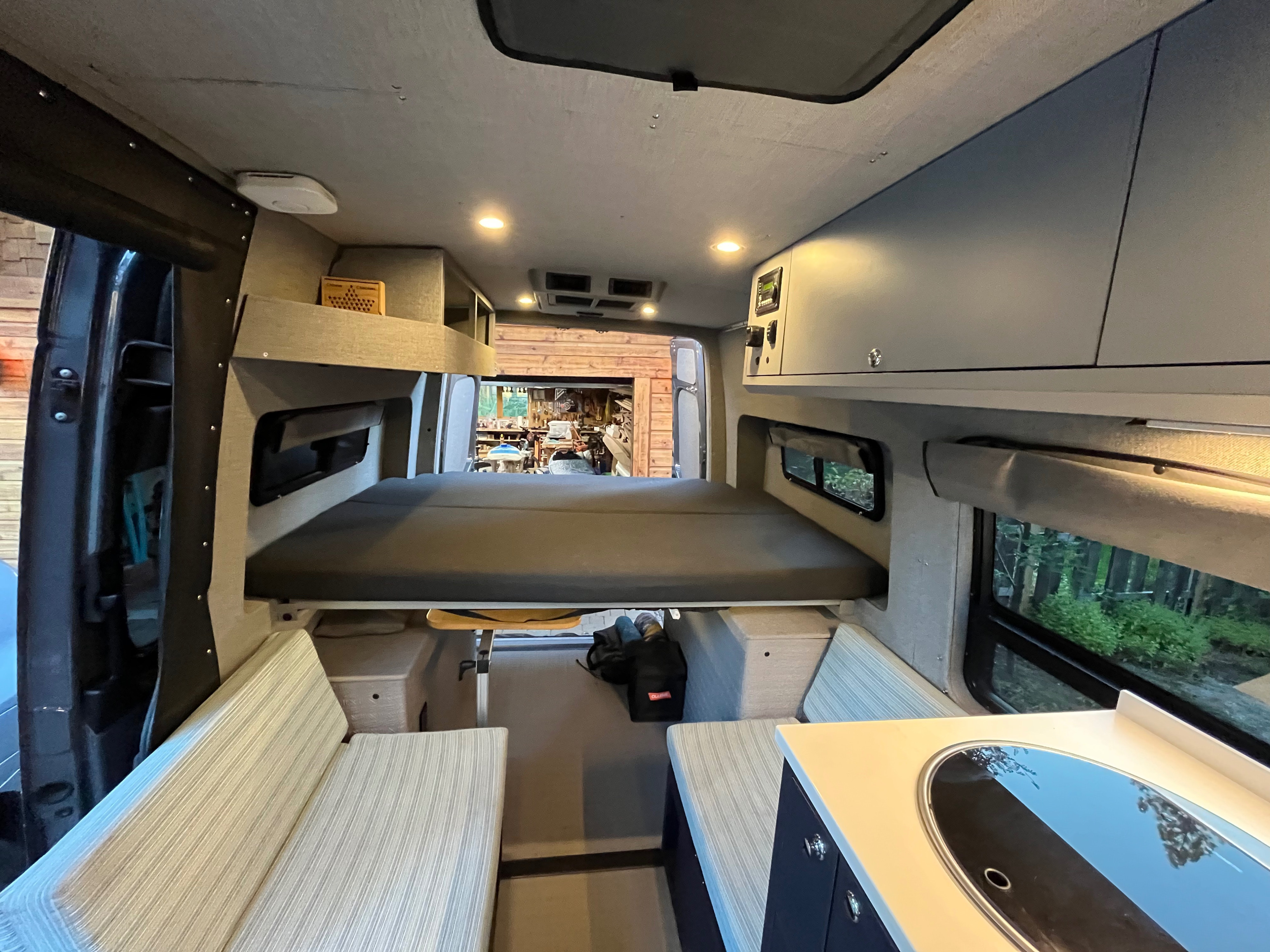 Cozy camper van interior for your next RV rental adventure. Features a comfortable bed, kitchen, and seating.. Mercedes Benz Sprinter 144 High Roof 4WD 2020