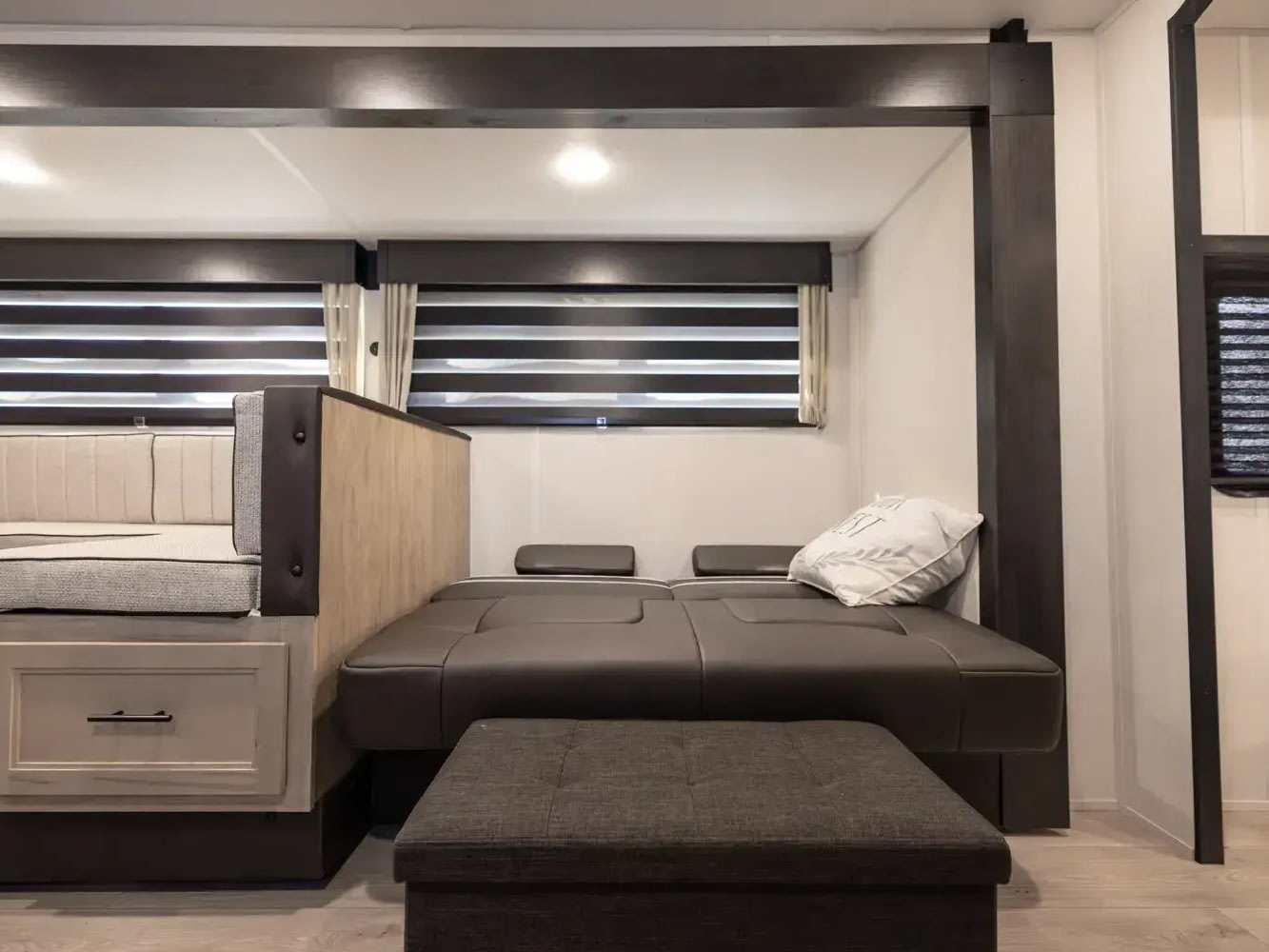 Spacious RV rental interior featuring a light-toned dinette, dark convertible bed, and ottoman for comfortable travel.. Forest River Cherokee Grey Wolf 2026