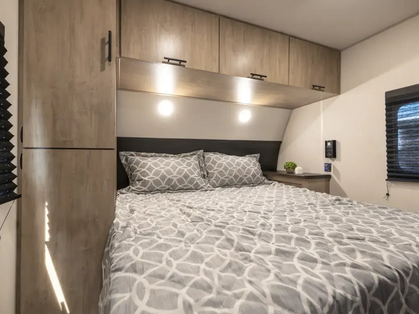 Comfortable RV rental bedroom featuring a bed with geometric bedding, overhead storage, and integrated lighting for cozy travels.. Forest River Cherokee Grey Wolf 2026