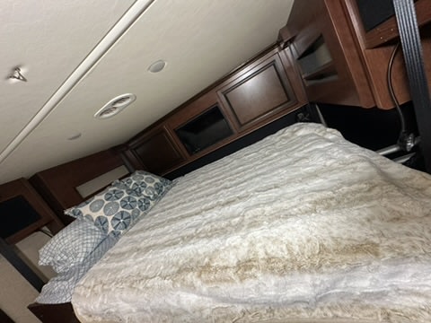 RV rental bedroom with a cozy, fluffy bed & patterned pillows. Overhead cabinets, ceiling lights, & vents provide comfort.. Fleetwood Other 2017