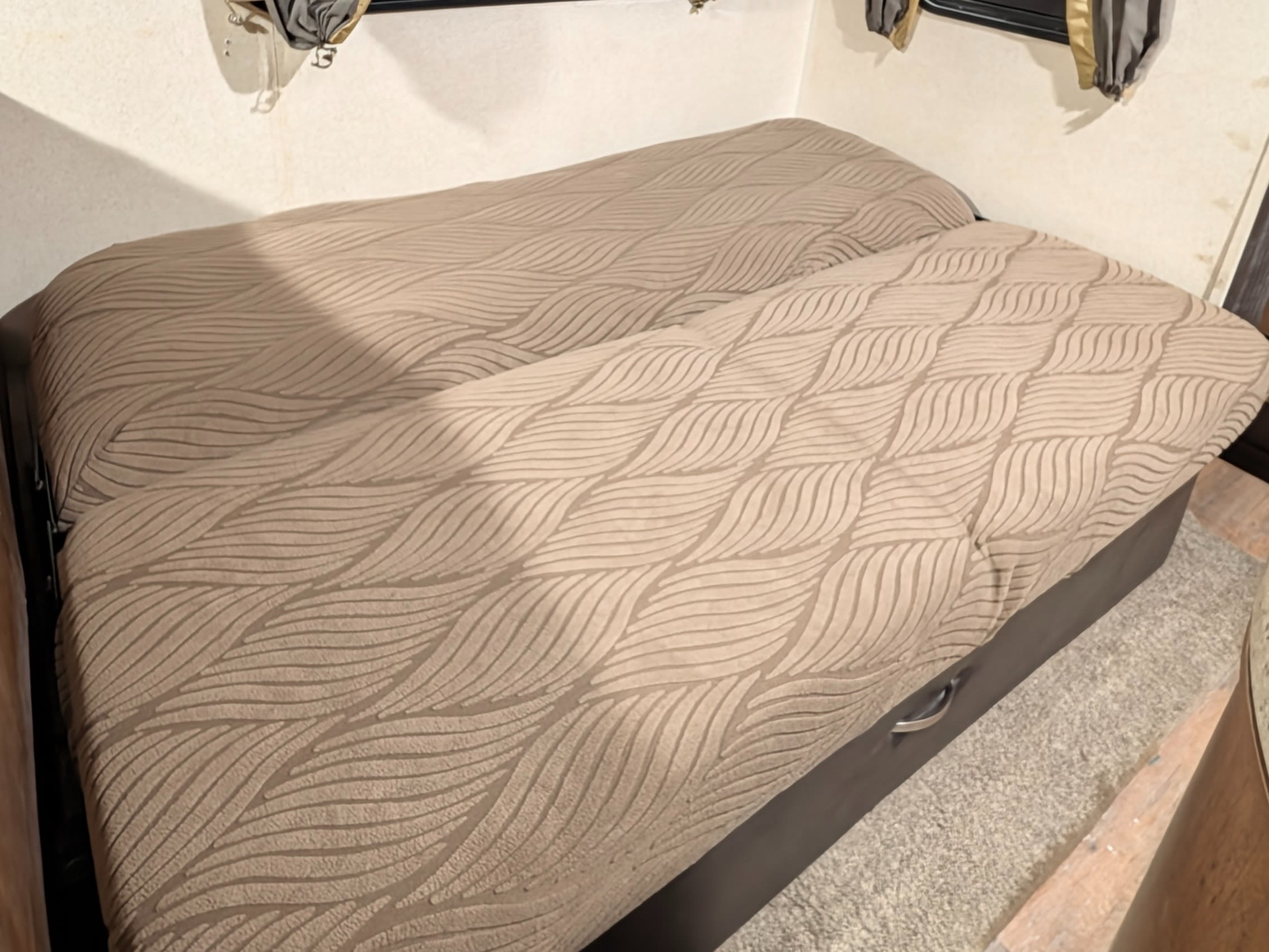 Cozy RV rental sleeping area features textured wavy bedding, window coverings, and under-bed storage for comfortable travel.. Forest River Salem 2017