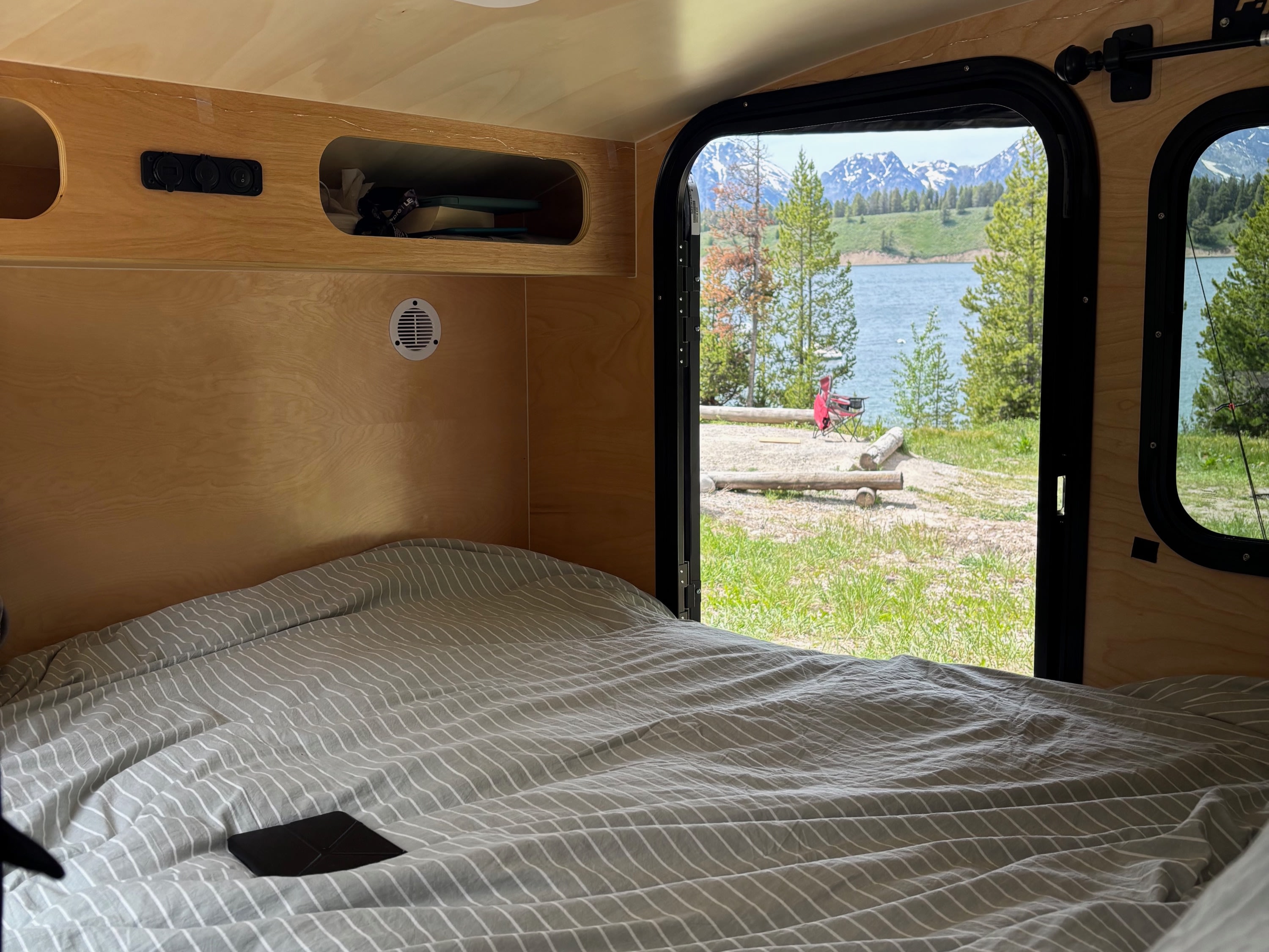 Cozy RV rental bedroom with a stunning lake, mountain, and forest view from the open door.. Hiker 5x8 Highway Deluxe 2025
