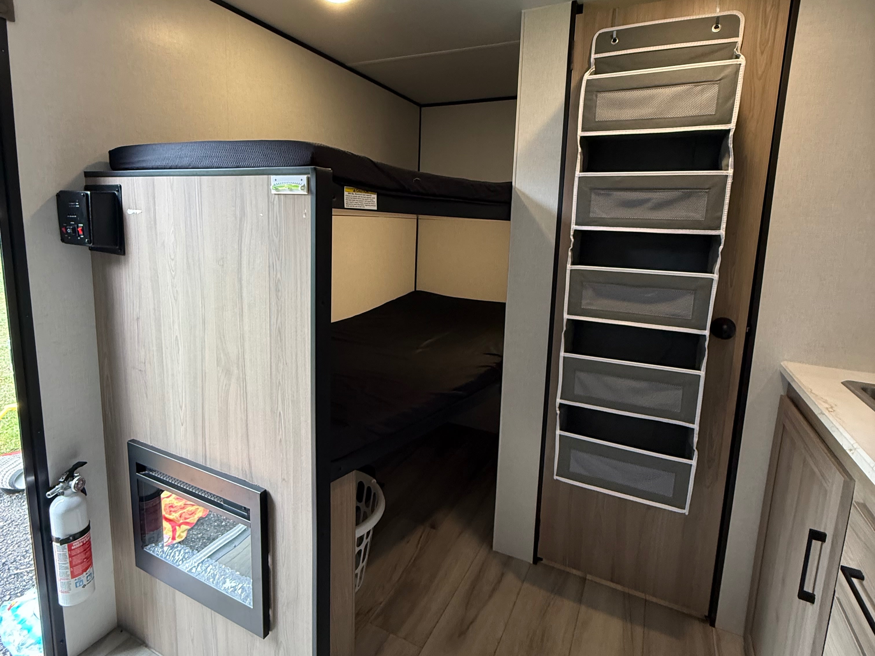 This RV rental interior showcases bunk beds, a cozy fireplace, and a hanging organizer maximizing compact living space.. Keystone Coleman 13b 2027