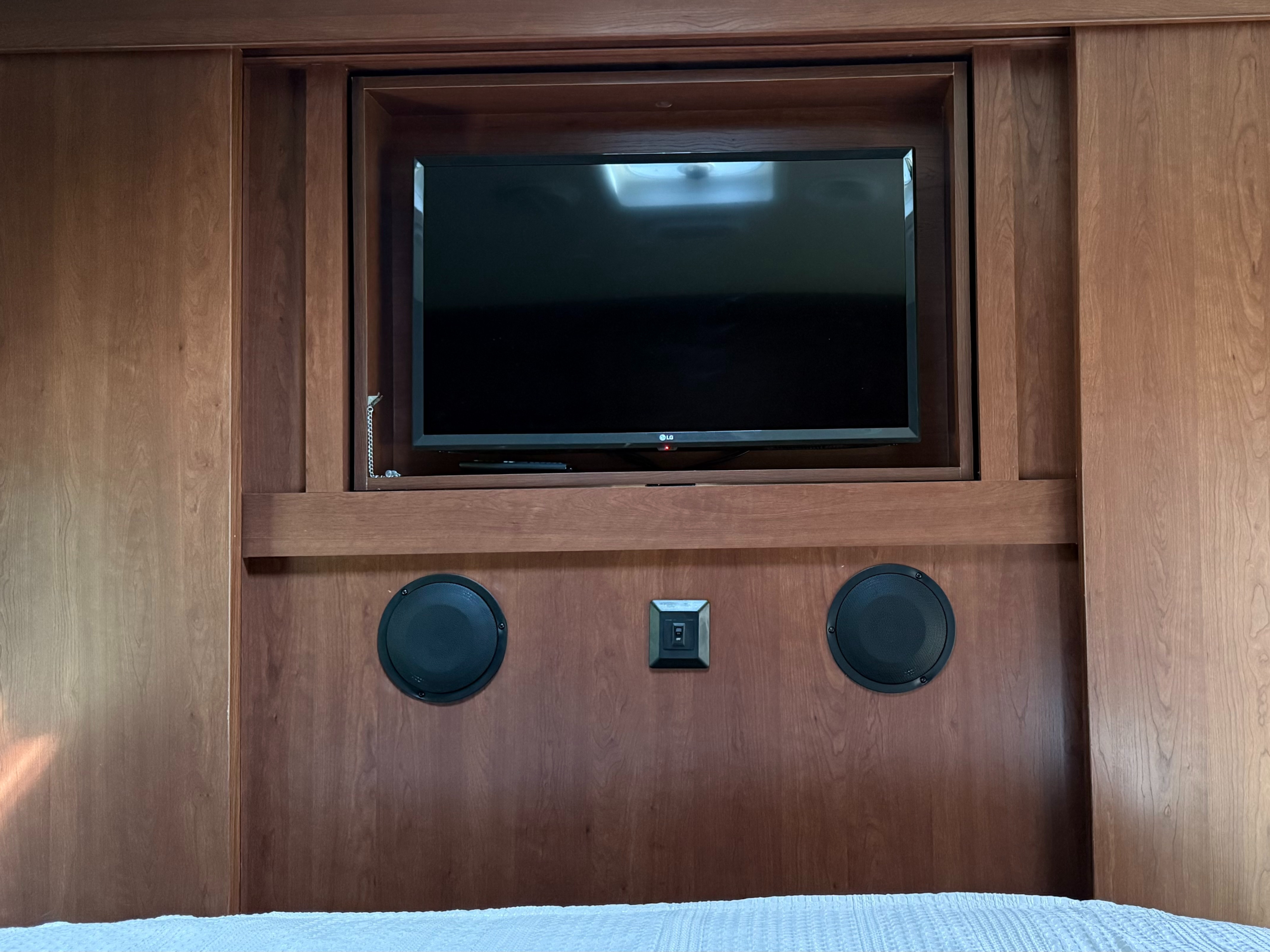 RV rental bedroom entertainment: TV, speakers, and controls integrated into the wooden wall paneling for a comfortable stay.. Palomino Solaire 2013