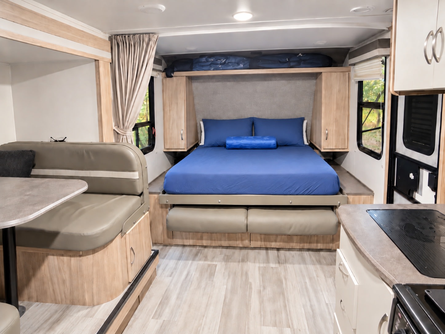 Explore the comfortable interior of this RV rental, featuring a full bed with blue linens, a versatile dinette, and a compact kitchen area.. Winnebago Industries Towables FLX 2108DS 2022
