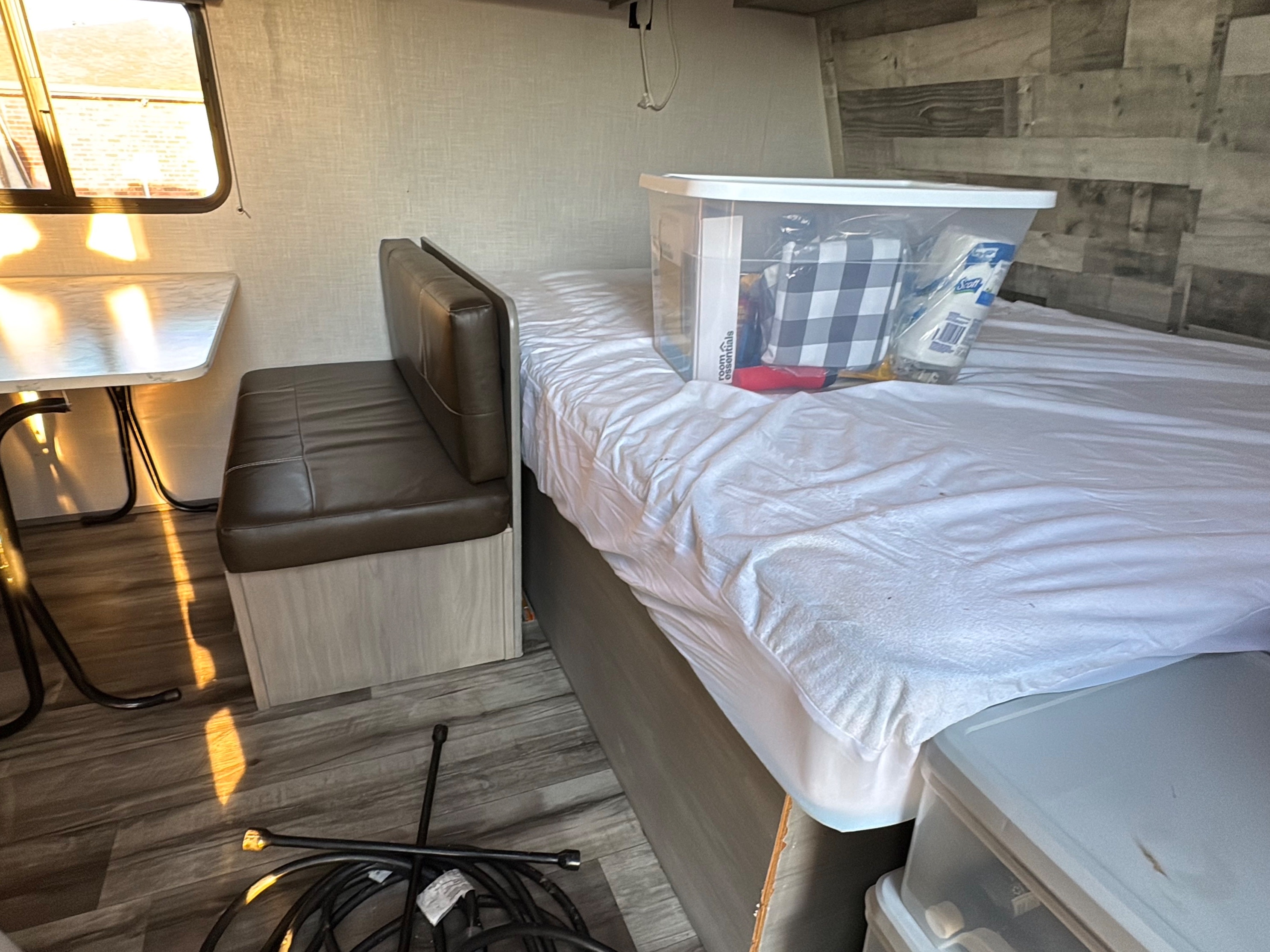 Cozy RV rental interior shows a dinette, bed with storage for supplies, and sunlight on the floor. Ready for your adventure.. Dutchmen Coleman Lantern 2022