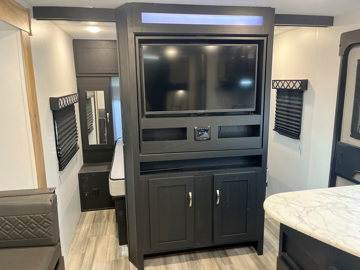 RV rental interior: modern design with a central TV entertainment system, dark wood cabinets, and functional, compact living areas.. Coachmen Freedom Express 2022