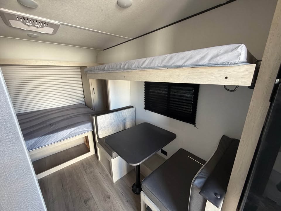 Cozy RV rental interior featuring bunk beds, a dinette, and a comfy bed, ideal for your next road trip adventure.. Coachmen Shasta 2027
