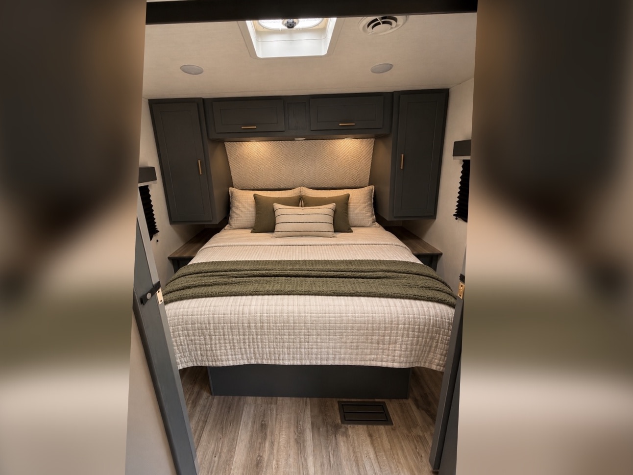 This cozy RV rental bedroom features a bed with olive throw, dark grey cabinets, and a stylish patterned headboard.. Keystone RV Bullet Crossfire 2024