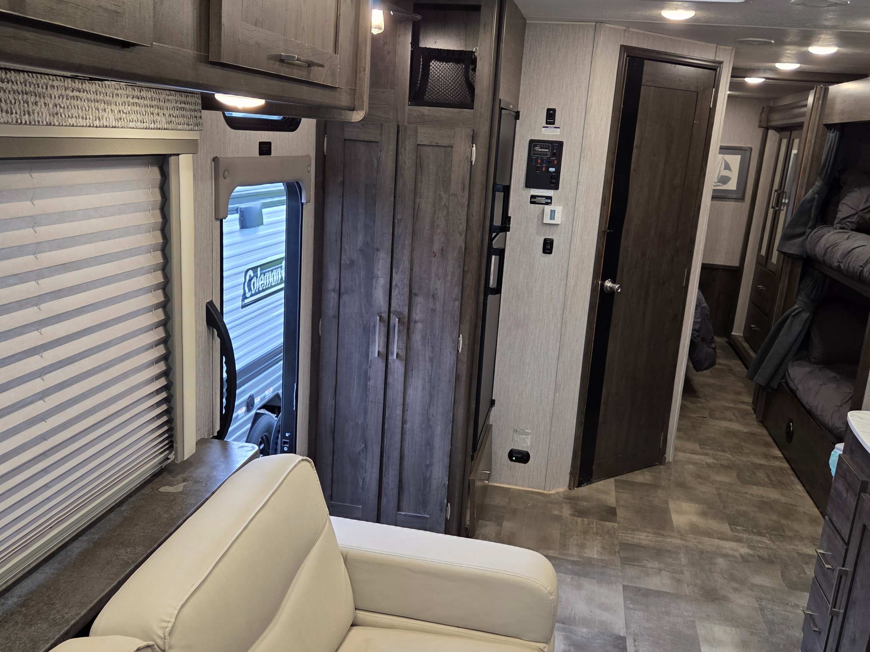 Cozy RV rental interior featuring a sofa, bunk beds, and essential controls, with a glimpse of the Coleman exterior.. Forest River Coachmen Pursuit 2022