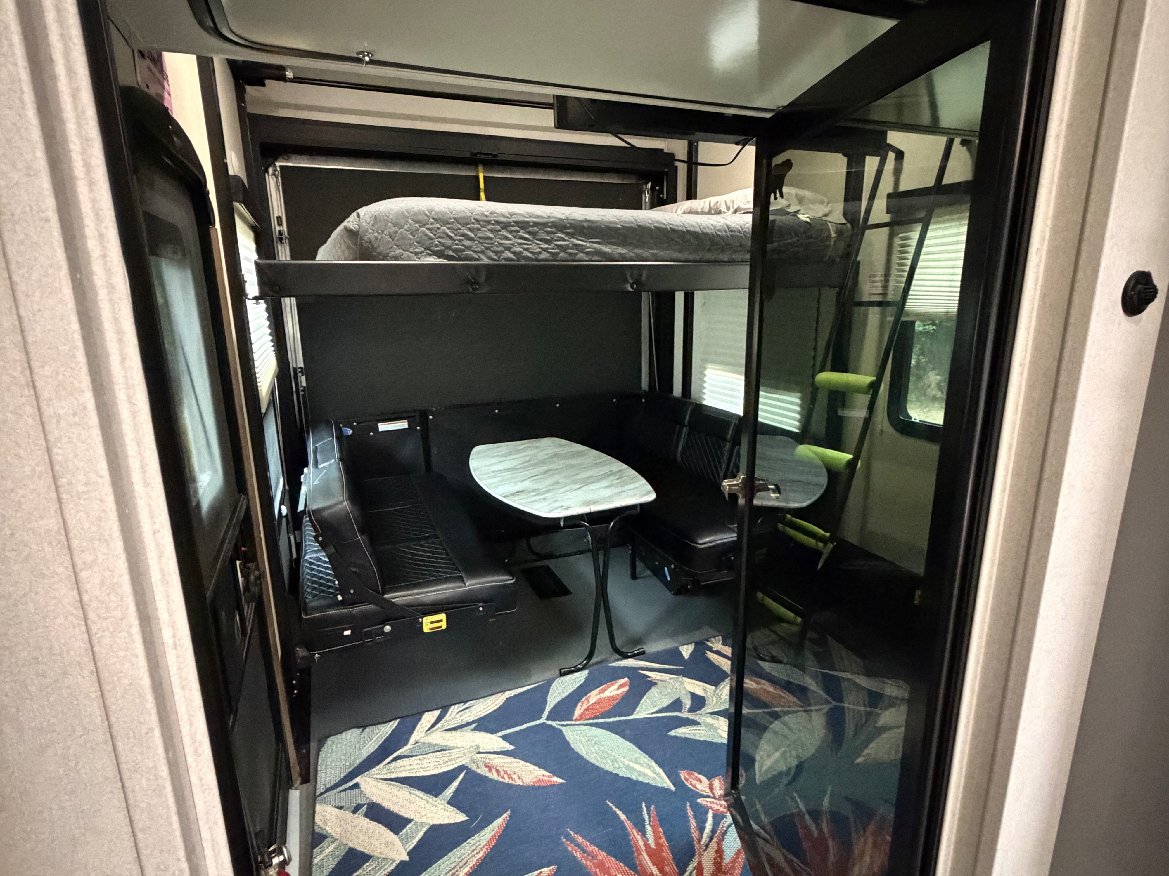 Spacious rv rental interior showing a convertible dinette, retractable bunk beds, and a vibrant rug. Ideal for toy hauler RV adventures.. Keystone Fuzion 2020
