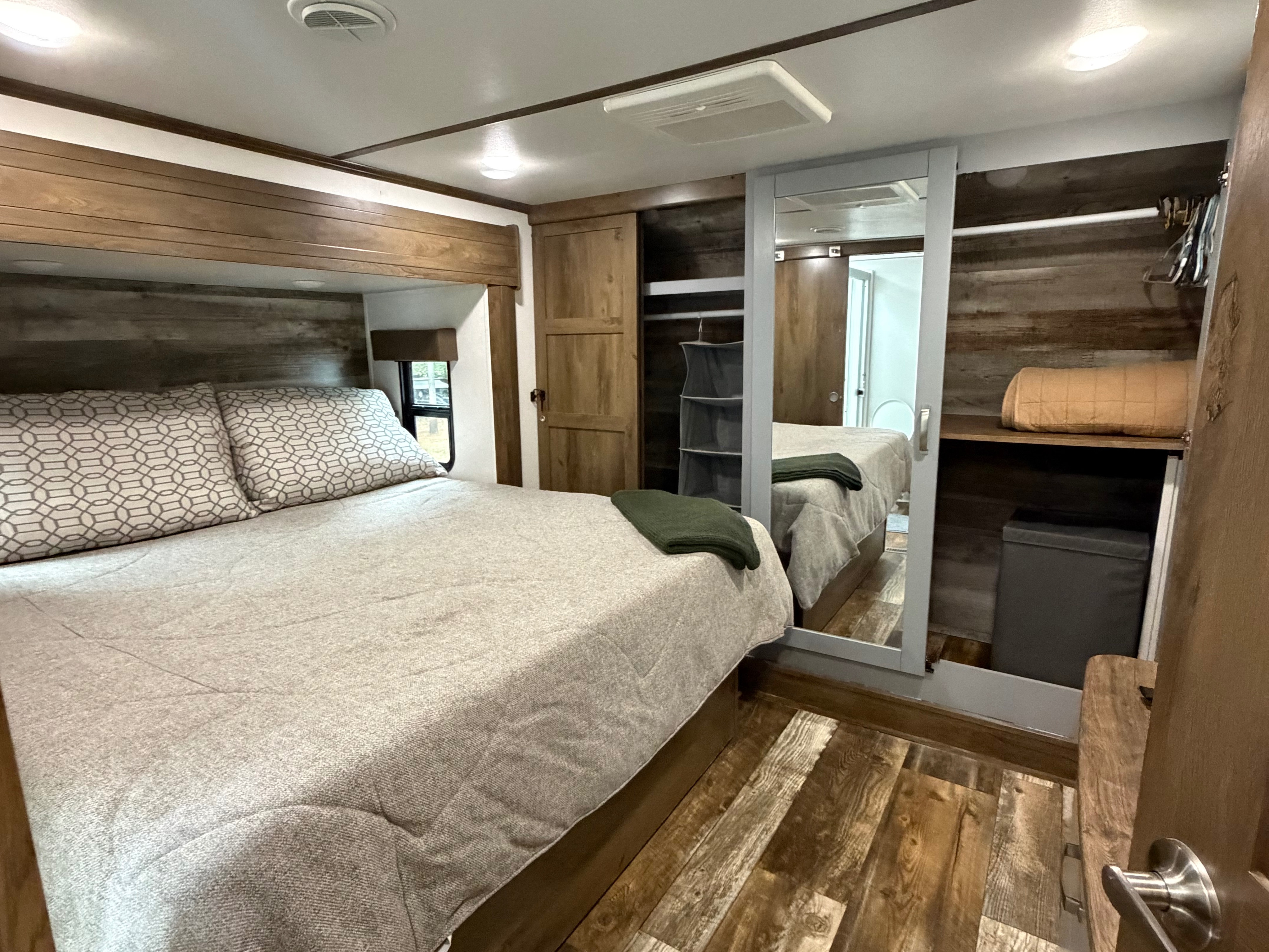 Cozy RV rental bedroom with comfortable bed, mirrored closet, and warm wood accents, ideal for a relaxing trip.. Keystone Fuzion 2020
