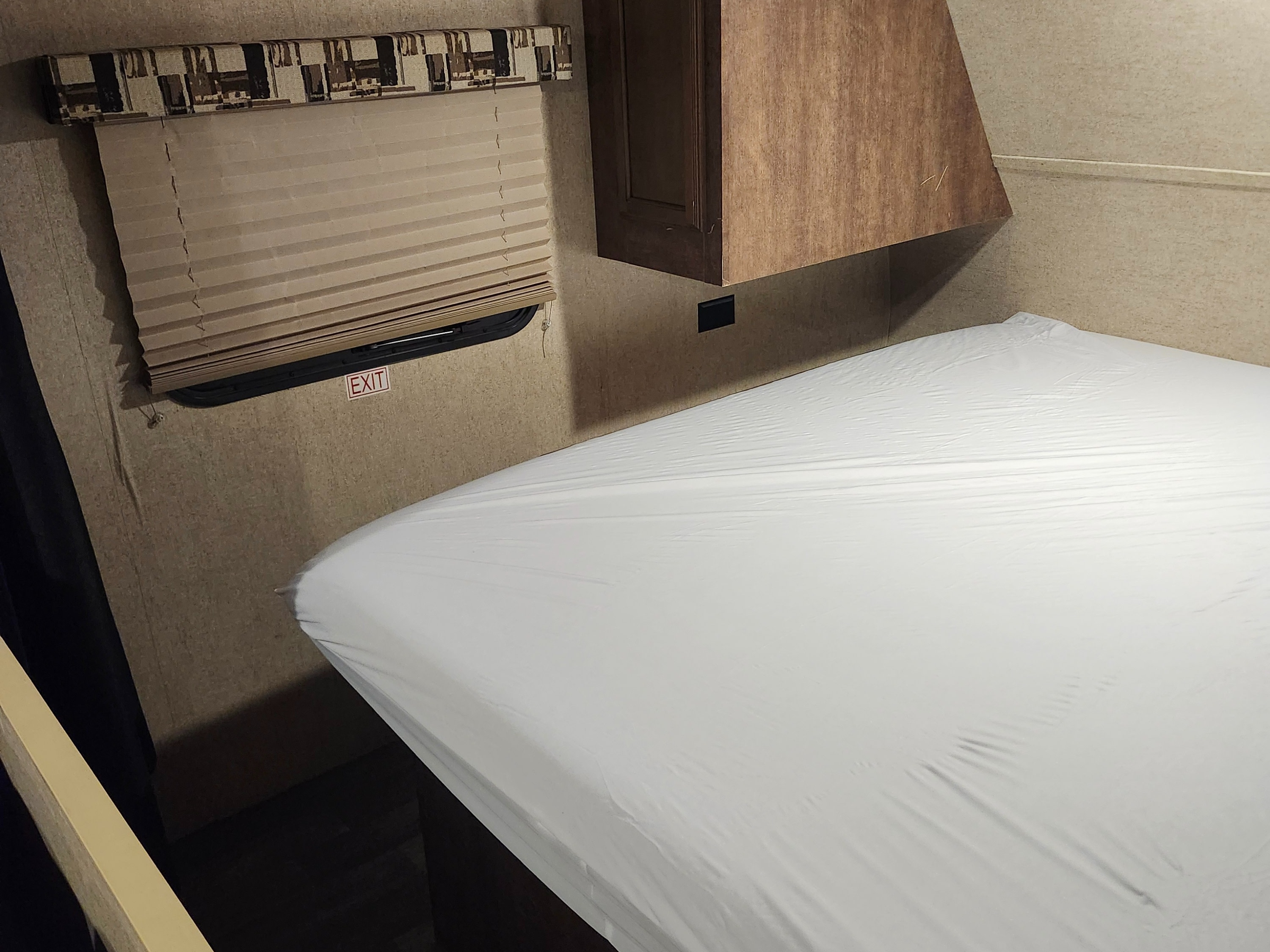 RV rental interior: a compact bedroom with a white bed, overhead cabinet, window blinds, and an exit sign.. Starcraft Autumn Ridge 2018