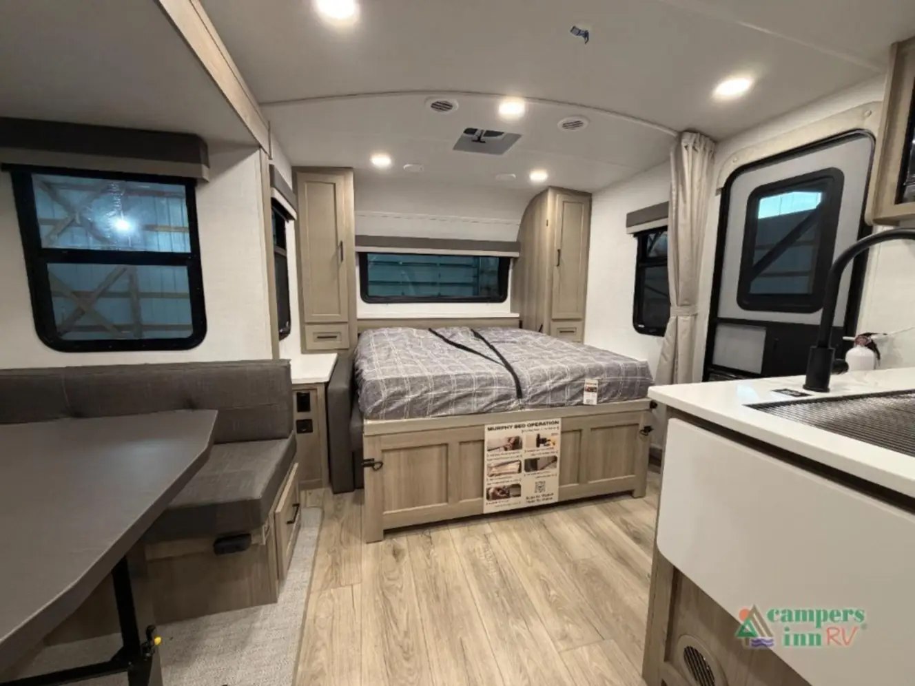 Modern RV rental interior with a comfortable bed, dinette, and compact kitchen area. Enjoy your adventure!. Forest River Rockwood Mini Lite 2025