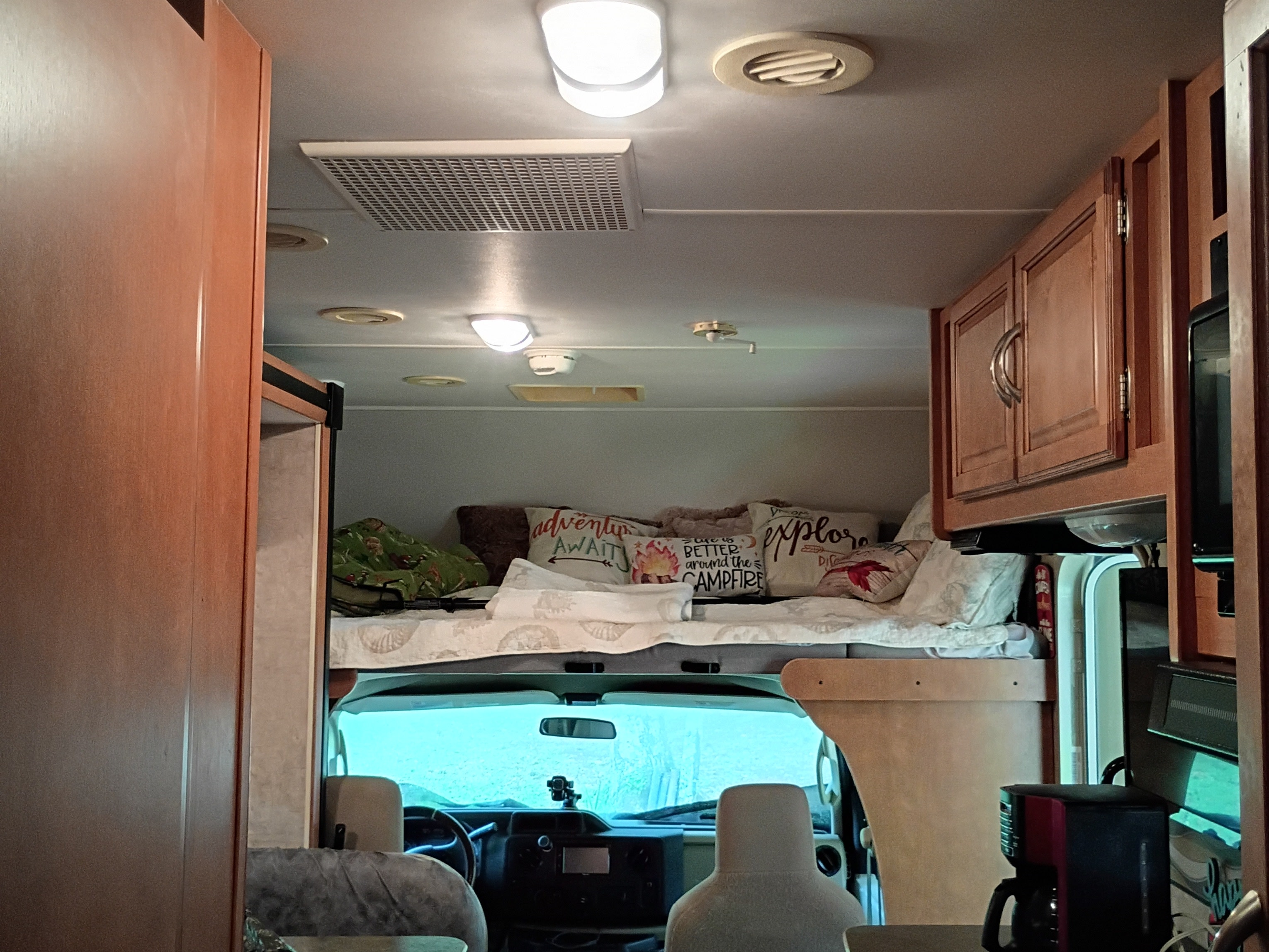 Cozy RV rental interior features cab-over bunk, dashboard, and wood cabinets.. Winnebago Minnie Winnie 2016