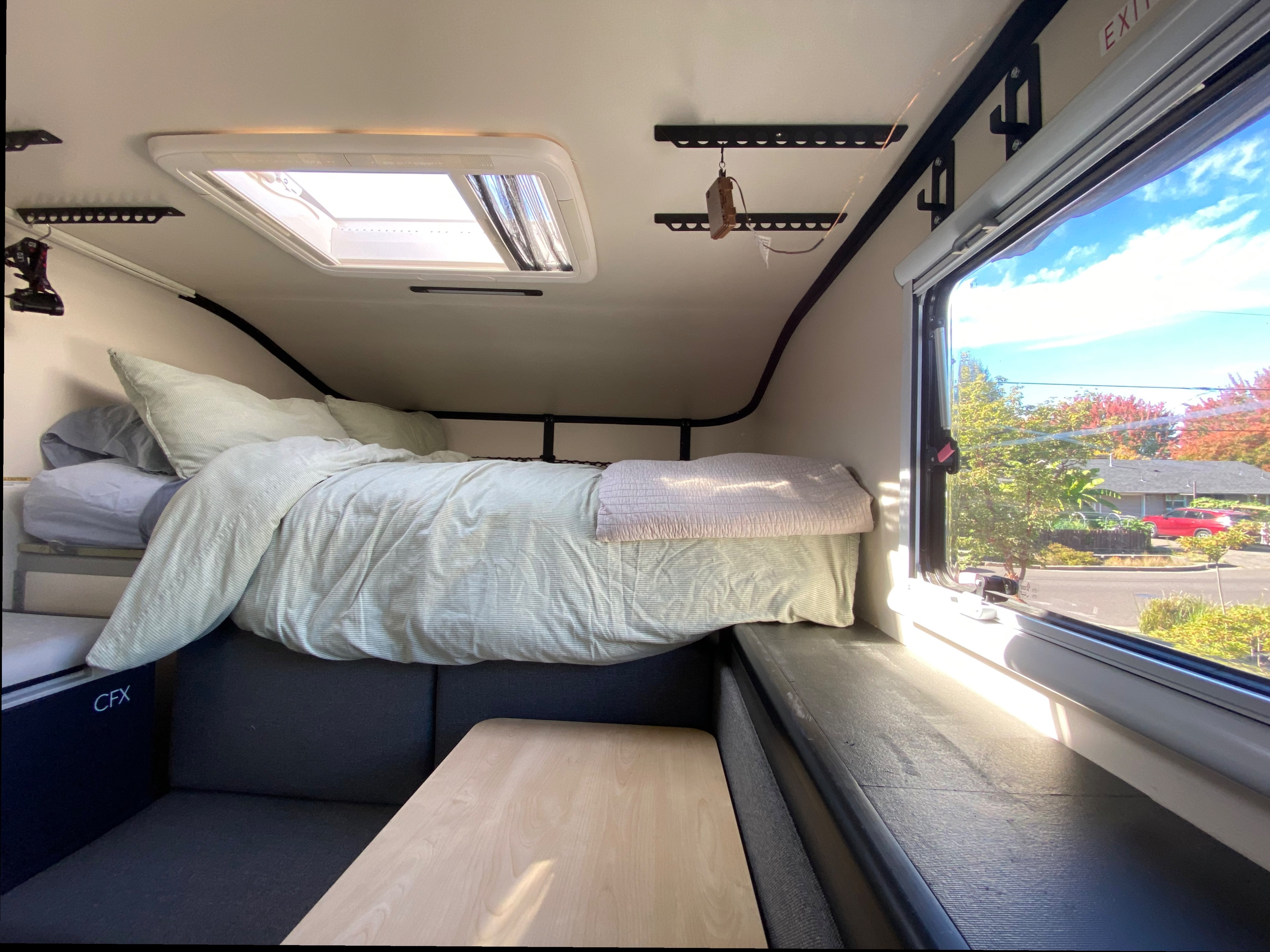 This RV rental interior offers a cozy bed, skylight, and window view, ideal for camper road trips.. Mobile Scout Dodge Ram 2500 2021