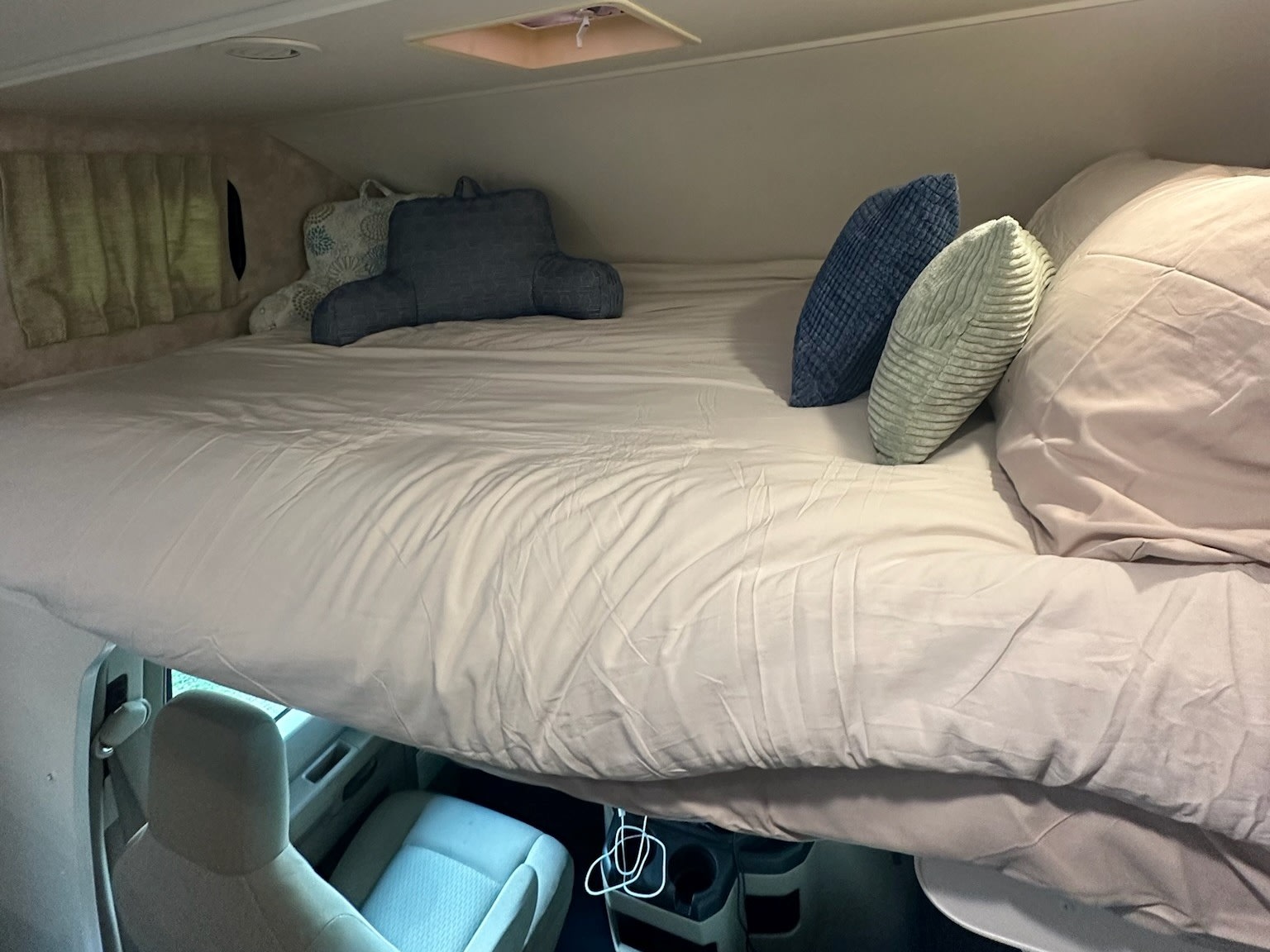 Comfortable cab-over bed in an RV rental, showing the cozy sleeping area with assorted pillows above the driver's seats.. Winnebago Minnie Winnie 2018